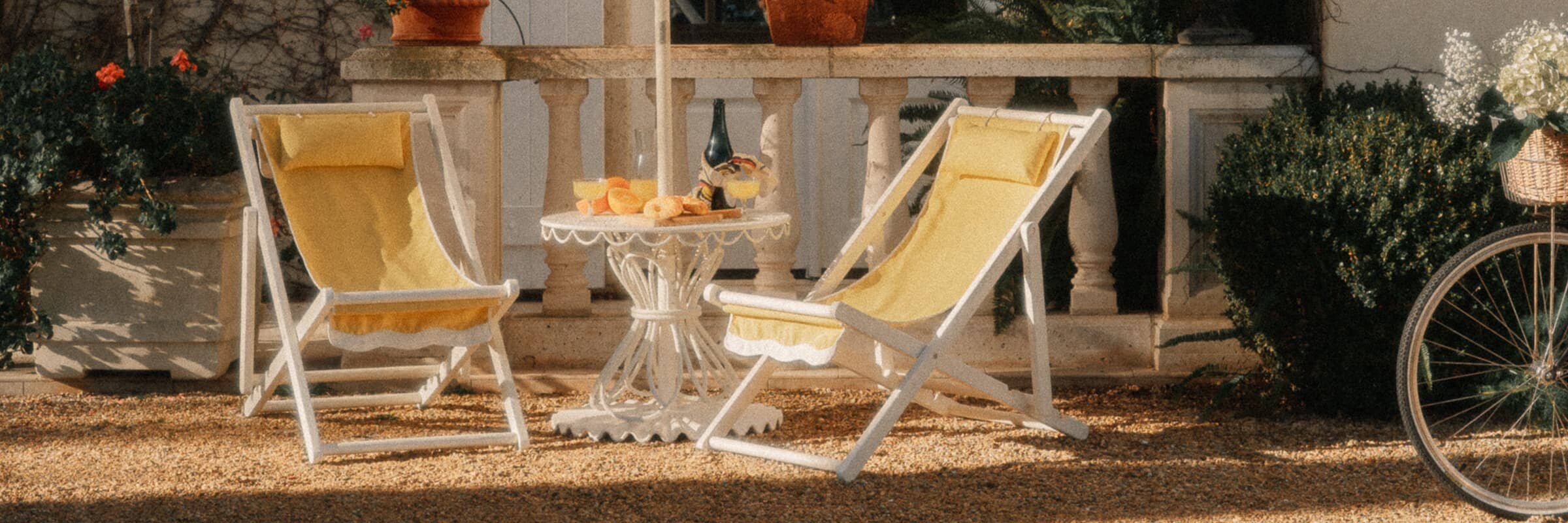 two yellow sling chairs and a table under an umbrella in a courtyard