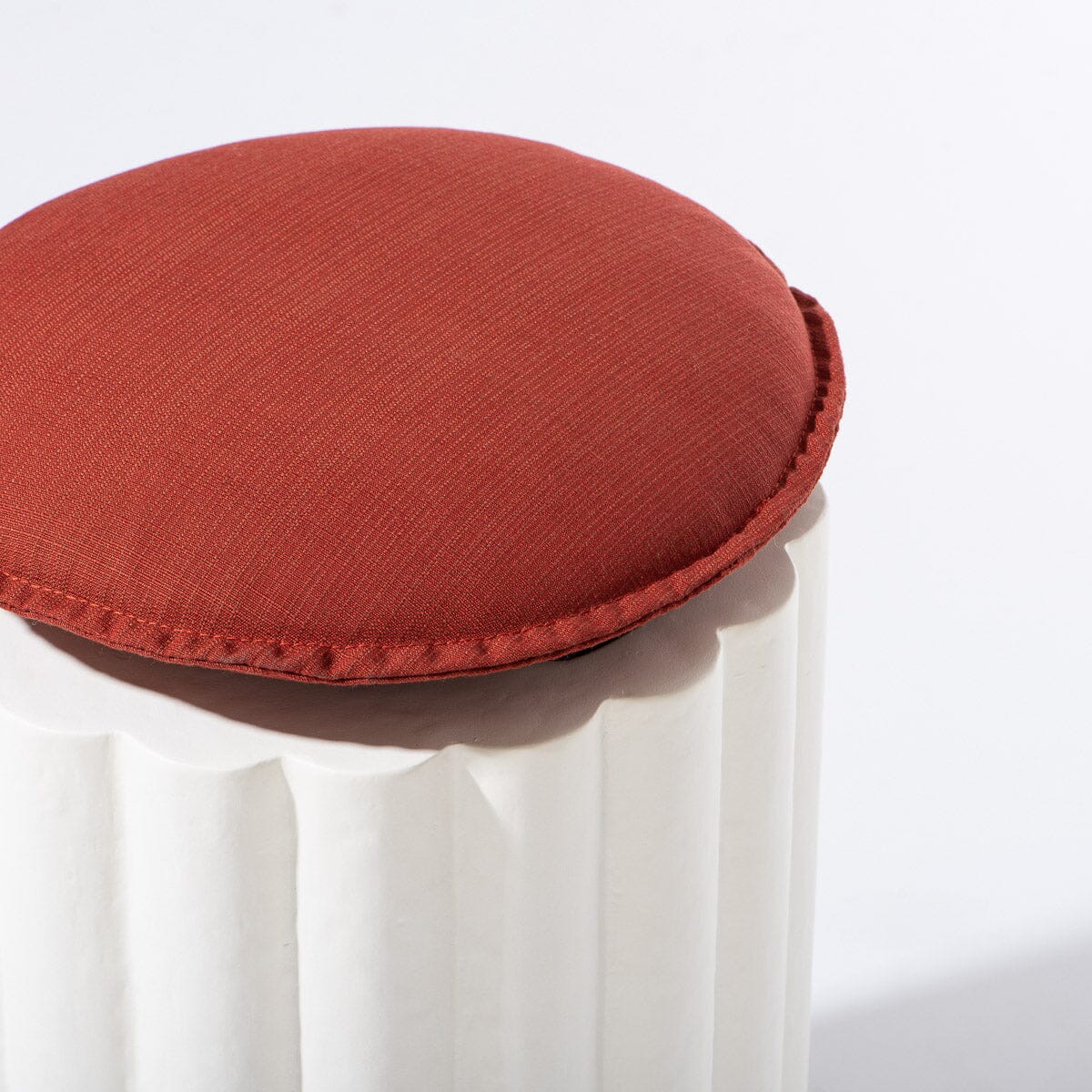 Red cushion on a white chair with a plain background