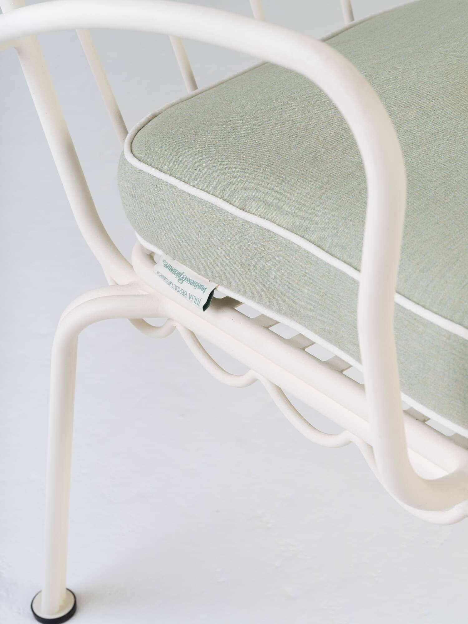 Tag detail of green chair cushion and white metal chair in studio