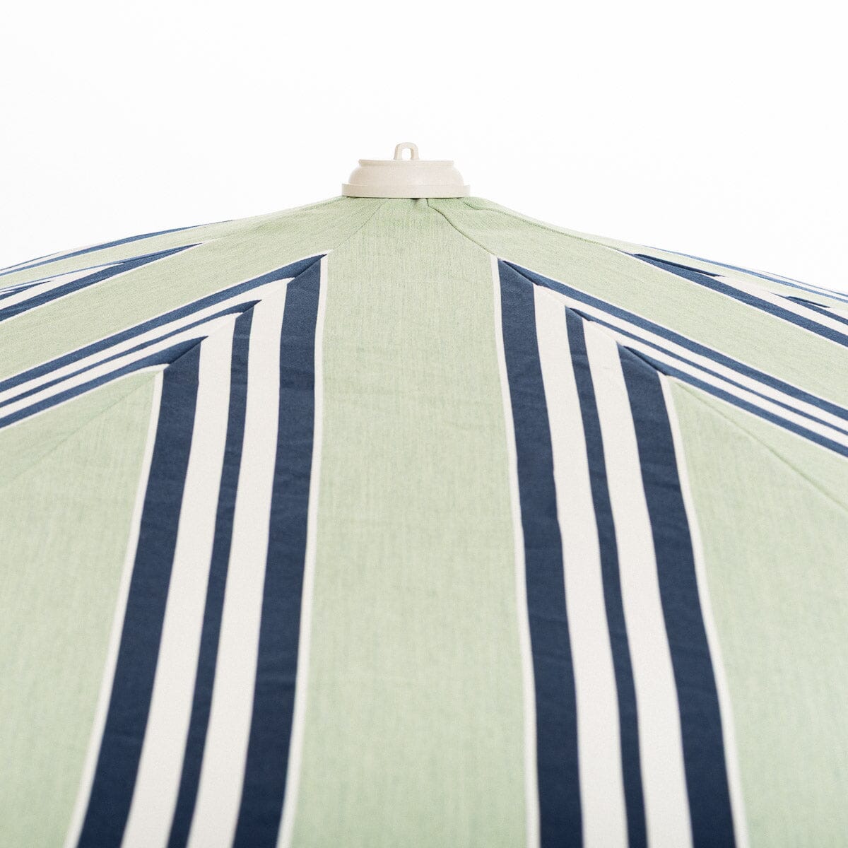 Close-up of a striped umbrella with blue and white stripes on a light green background