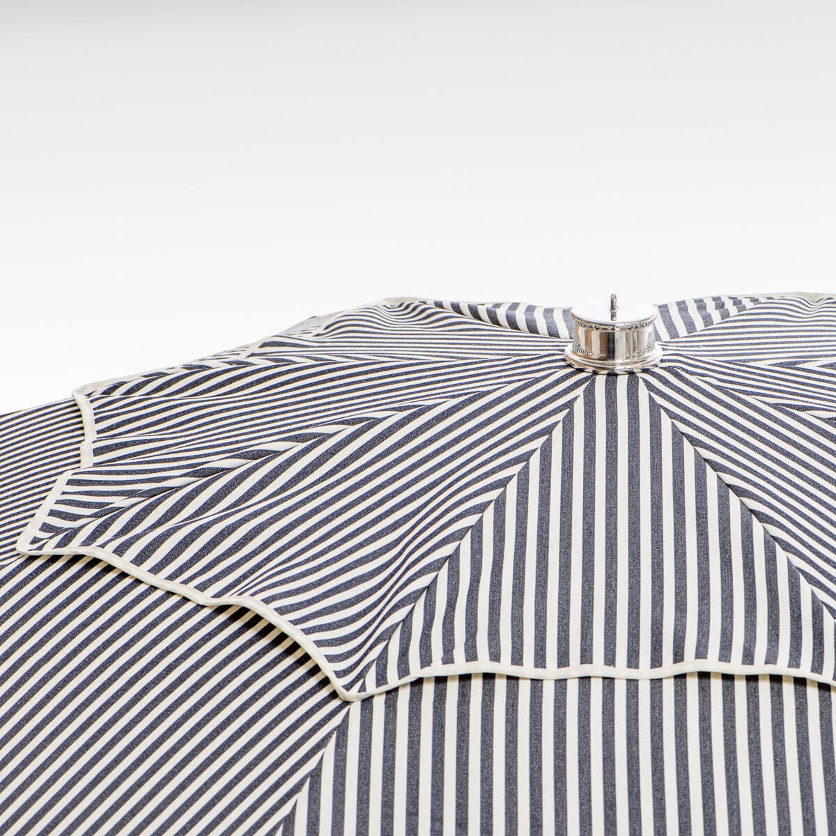 close up of chrome top cap on navy stripe patio umbrella
