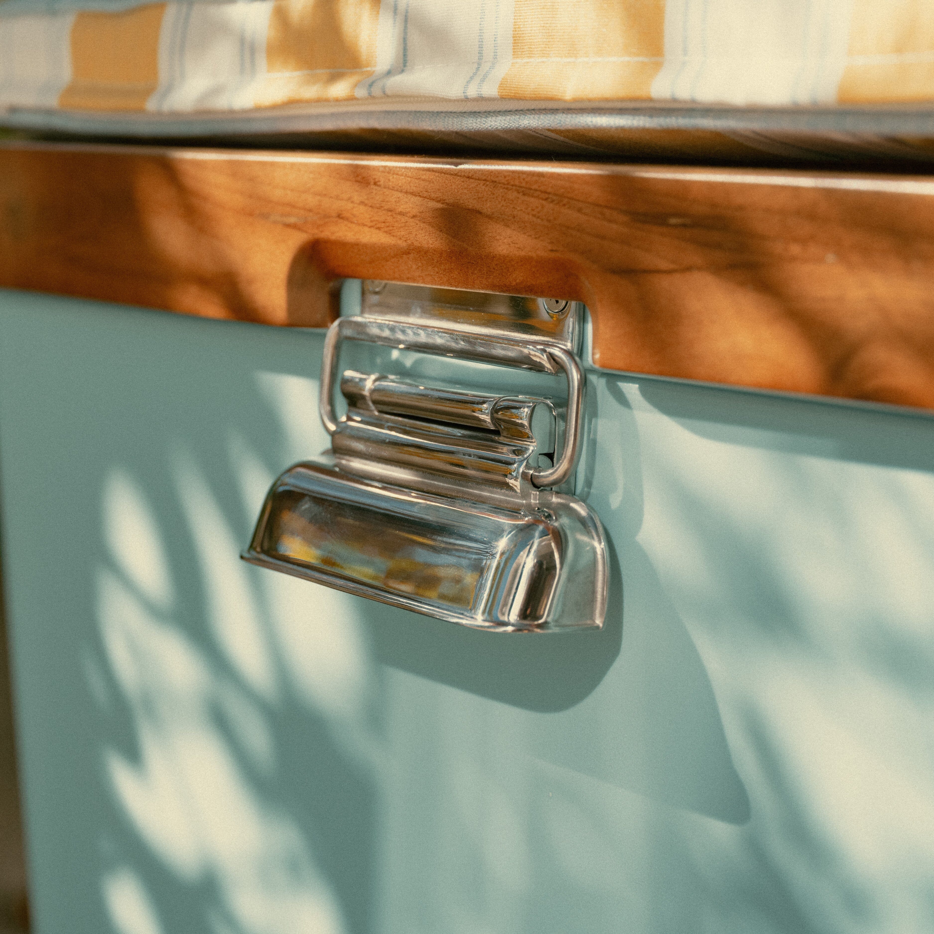 Close-up of a metallic handle on a wooden surface with a blurred natural background