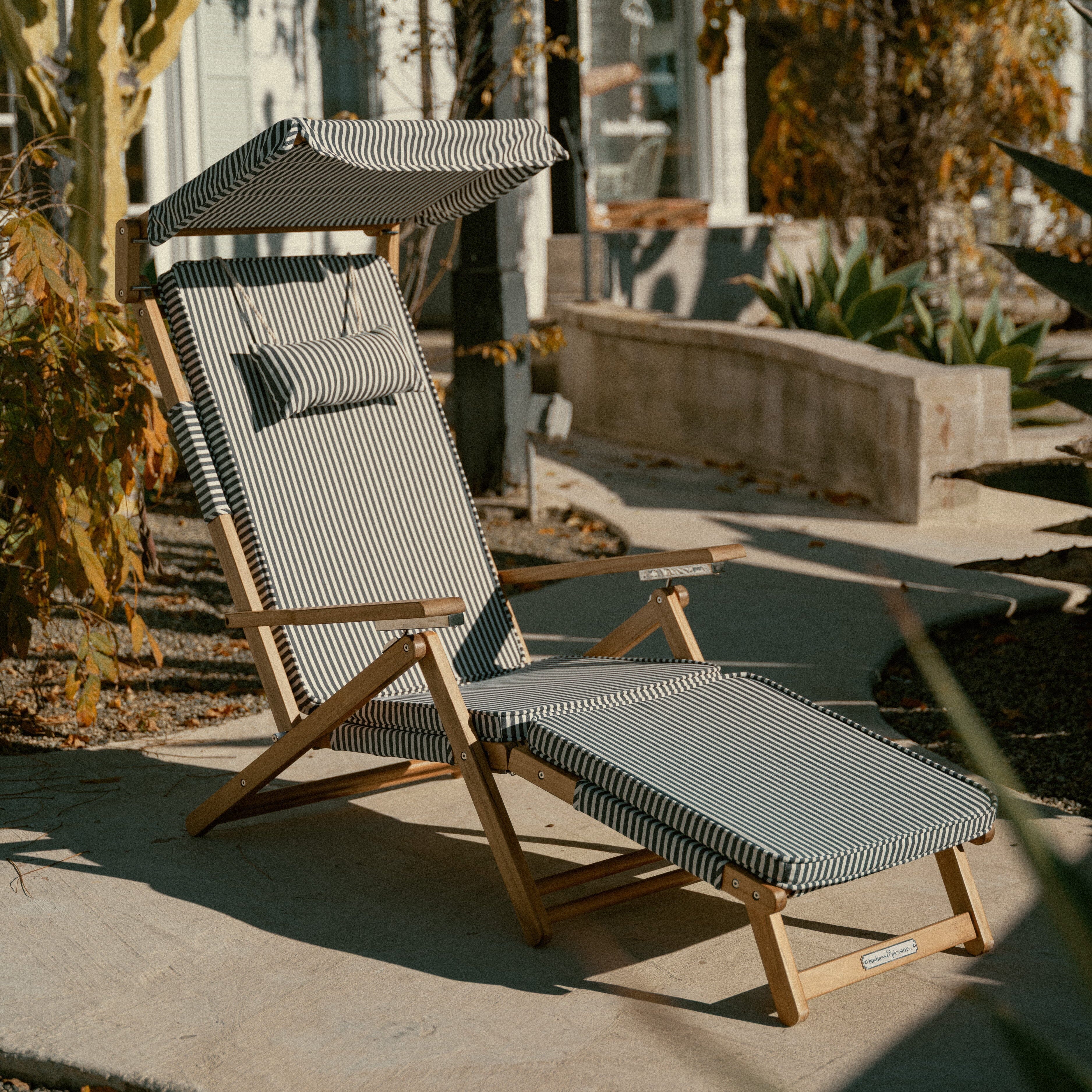 Wooden lounge chair with striped cushions on a patio