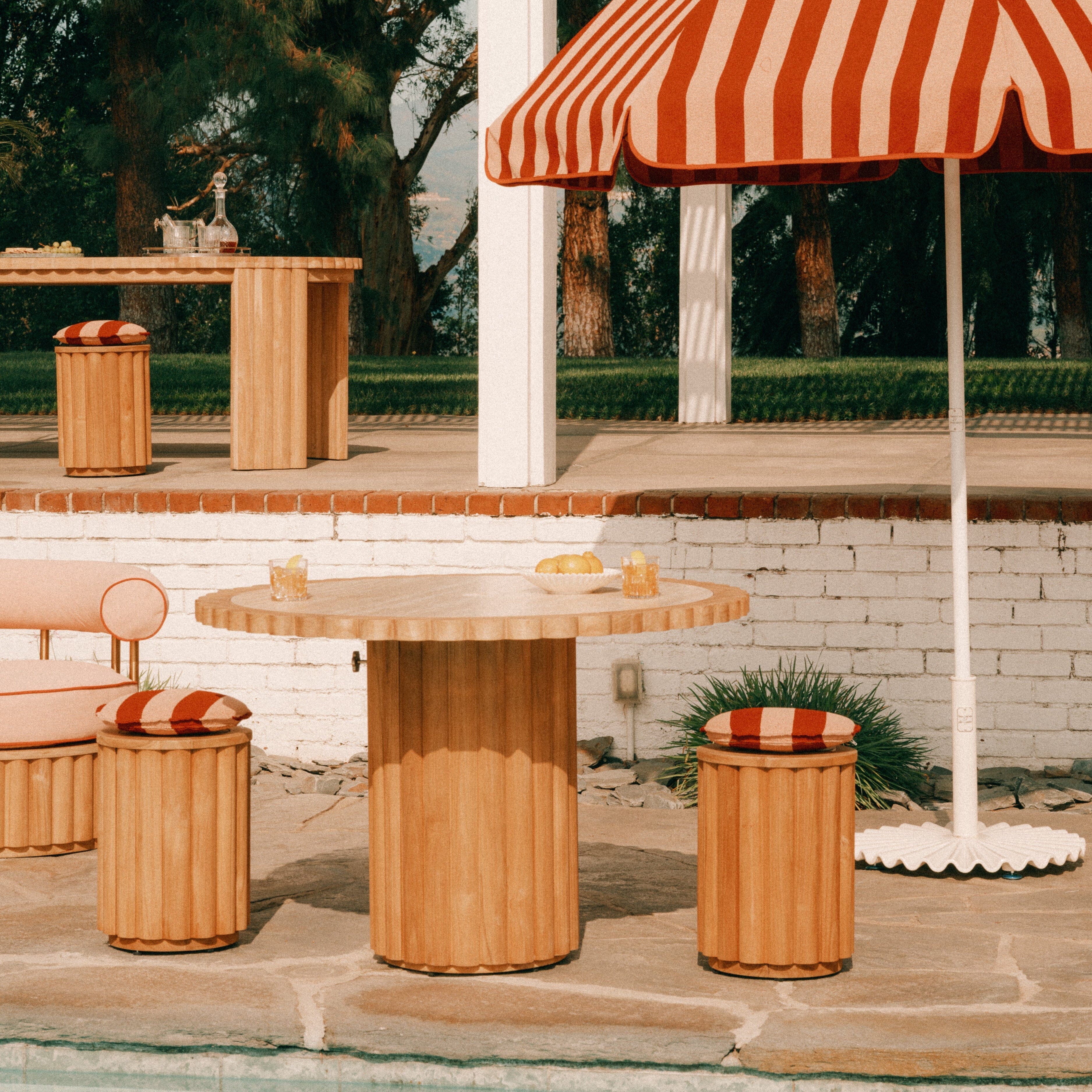 Outdoor setting with wooden table, striped umbrella, and chairs on a patio.