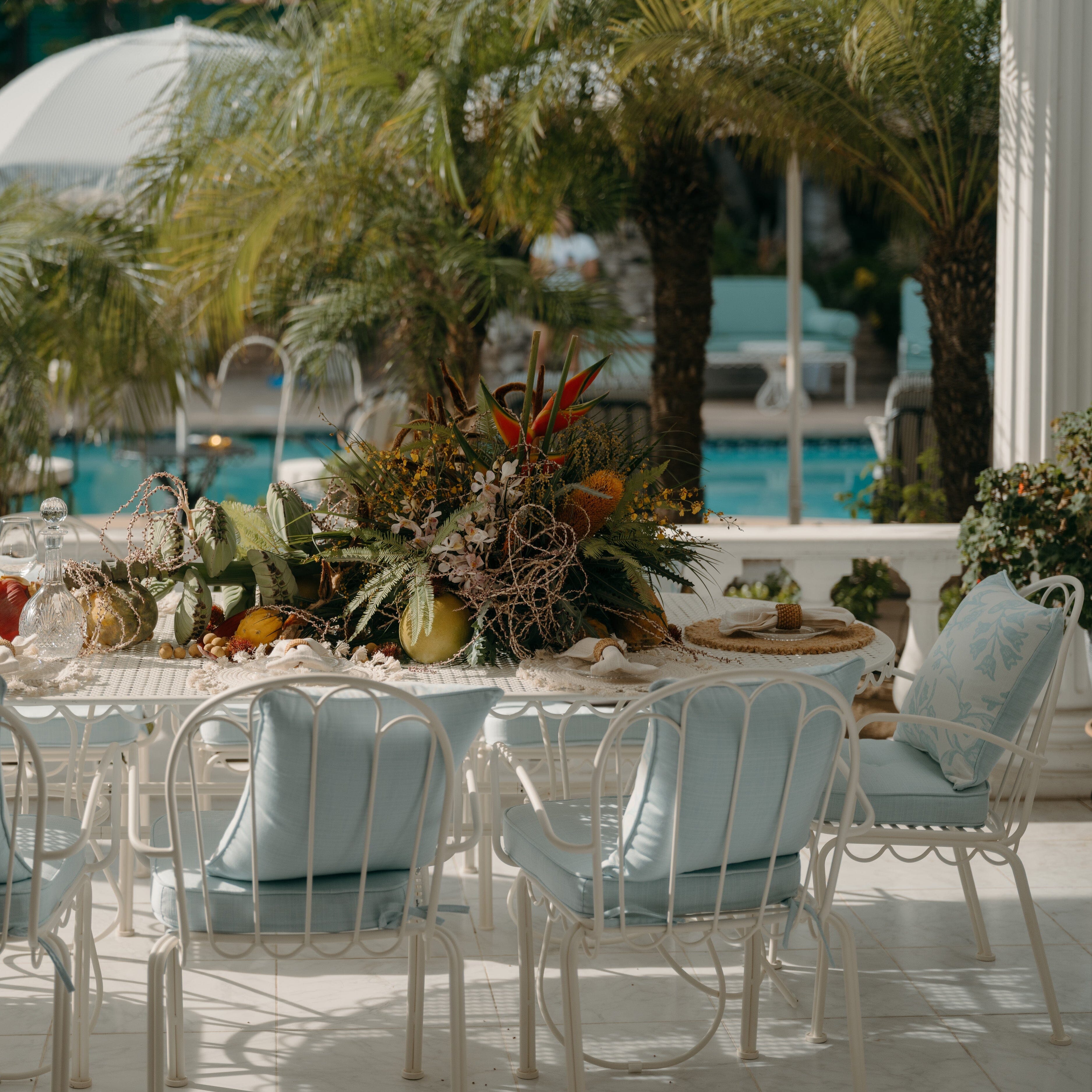 Outdoor dining setup with a table and chairs near a poolside.