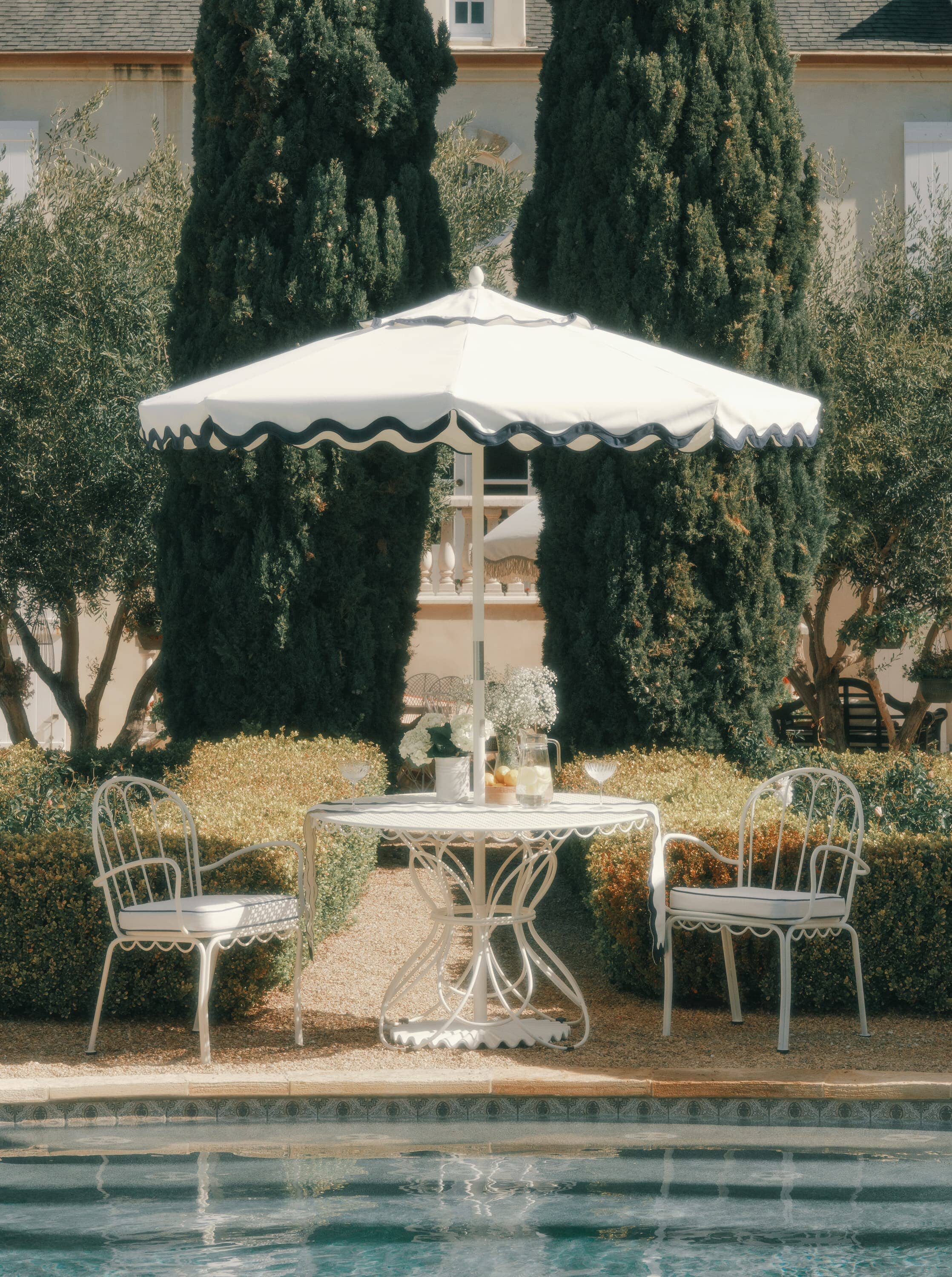 Outdoor dining table with chairs next to a pool