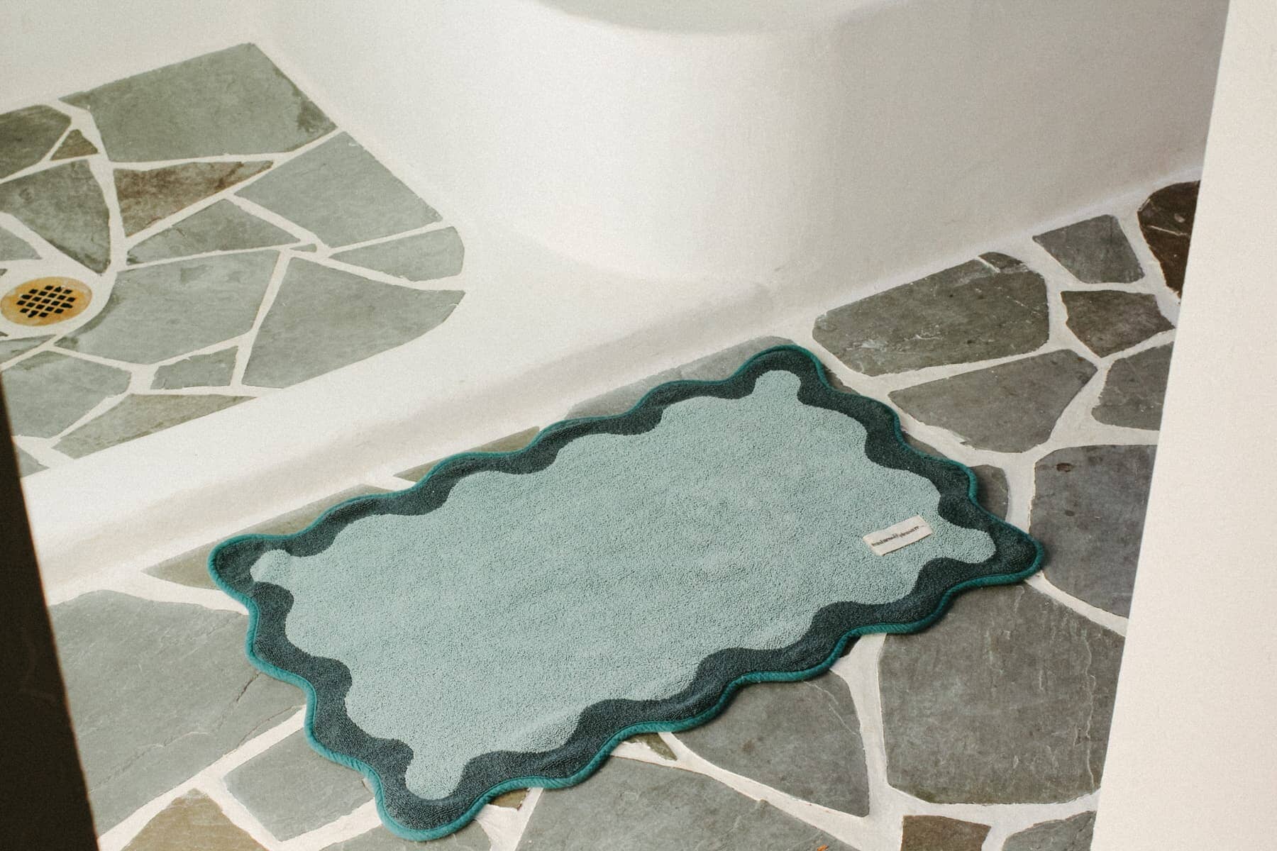 Green bath mat on a stone bathroom floor
