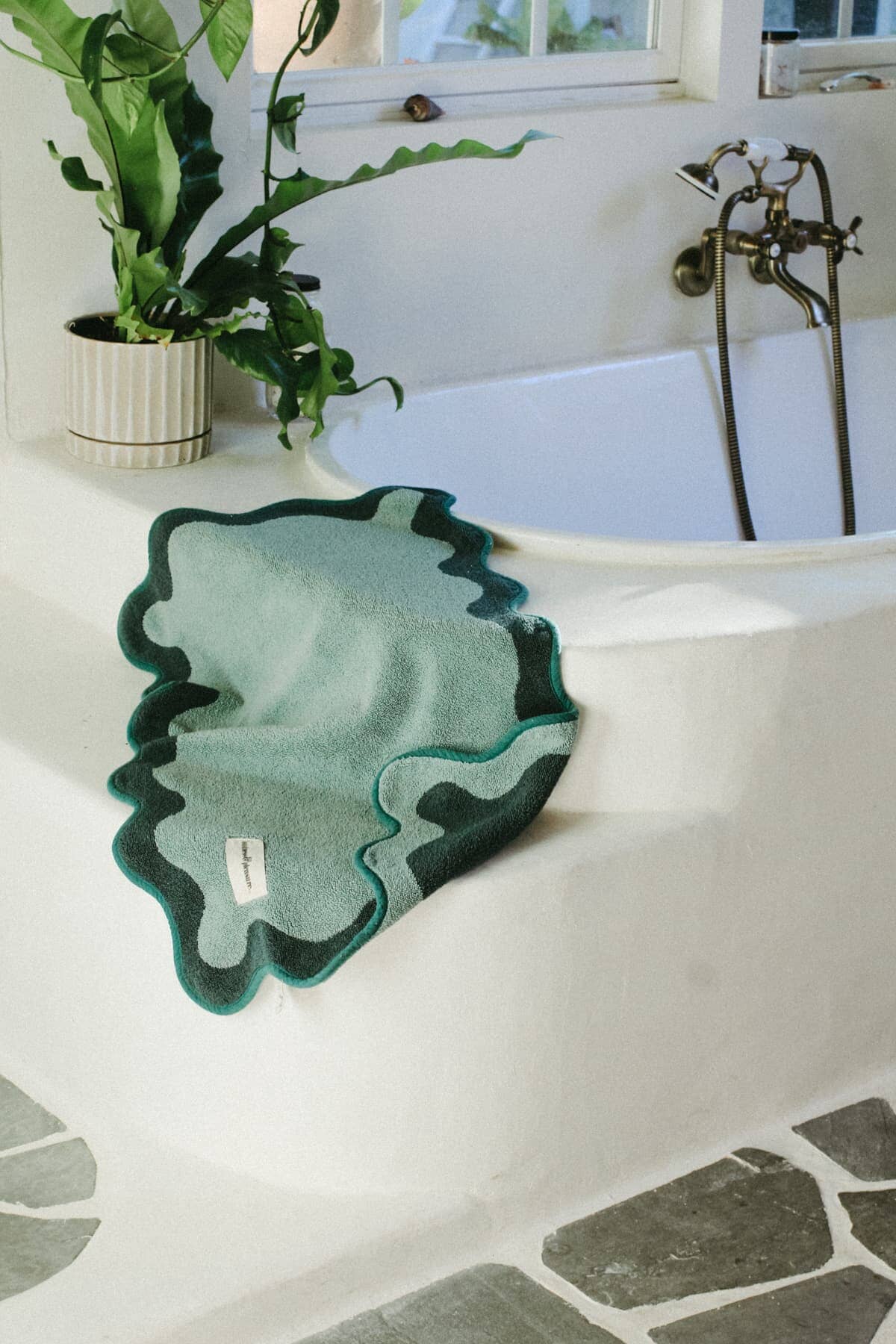 Green bath mat on a stone bathroom floor