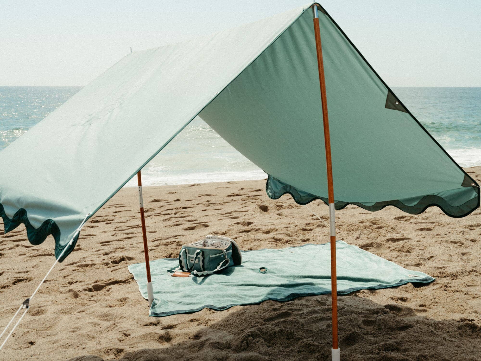 riviera green tent with blanket and cooler on the beach