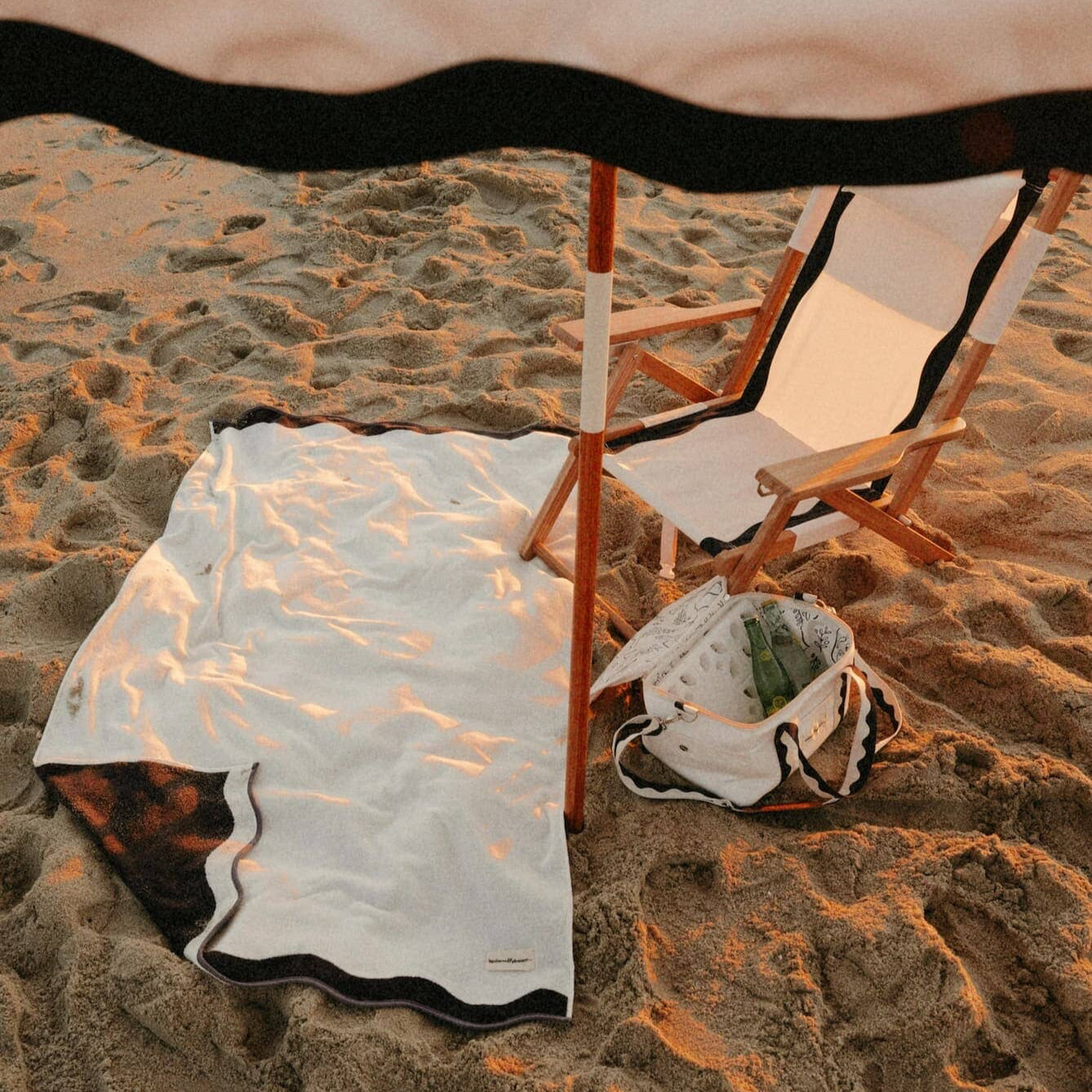 beach setting with riviera white cooler bag, towel, tommy chair.