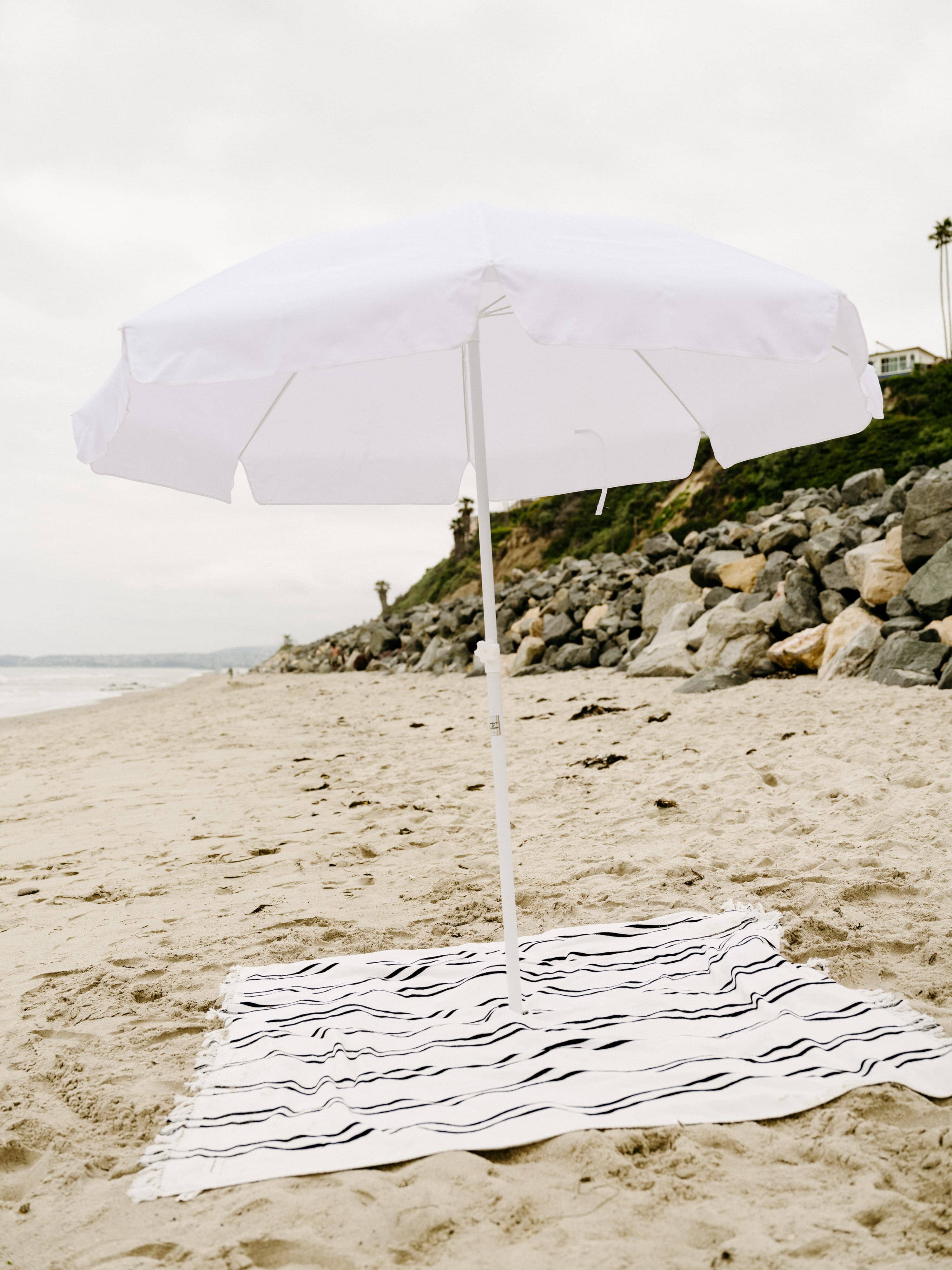 White family umbrella at the beach with beach blanket