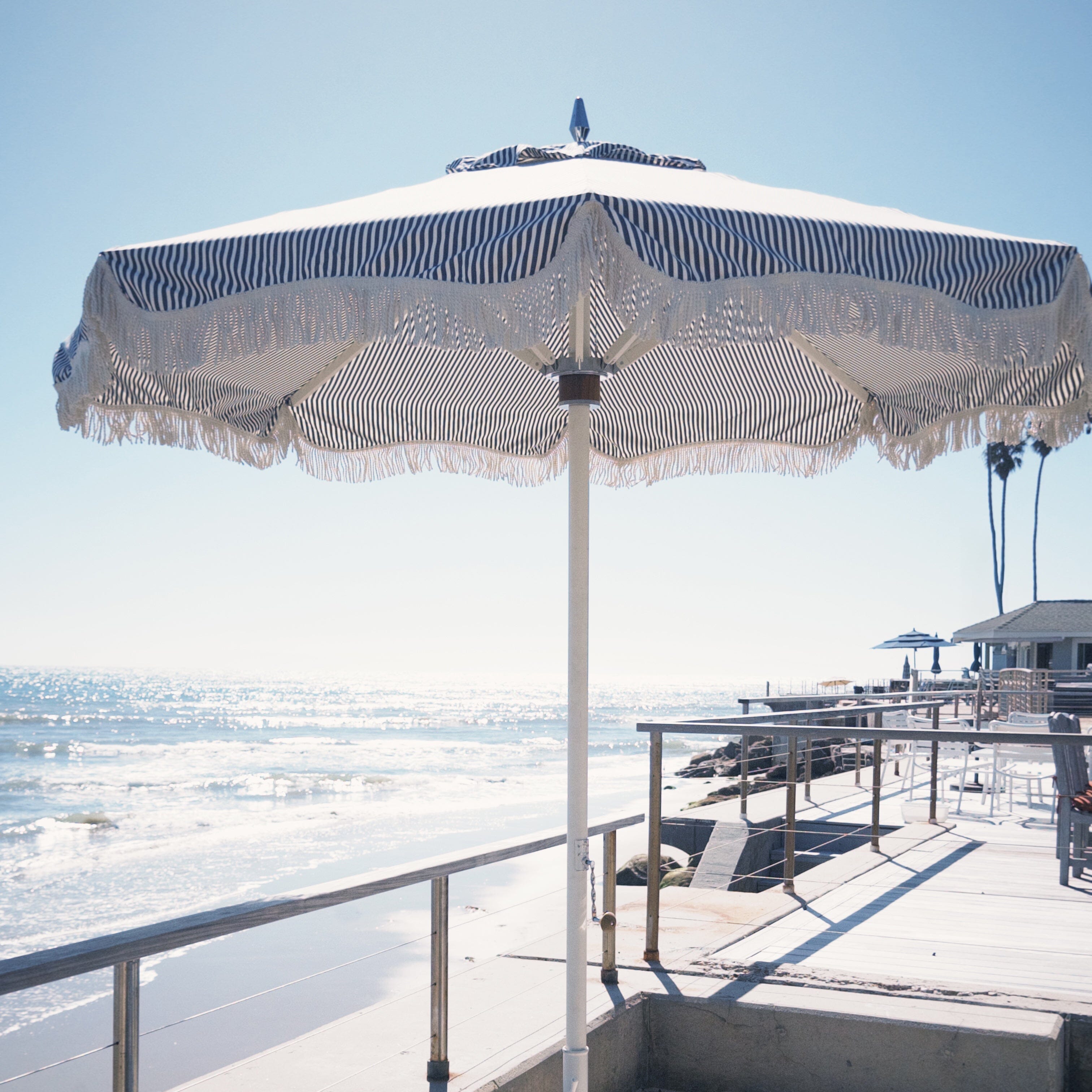 Beachside patio with umbrella and chairs overlooking the ocean.