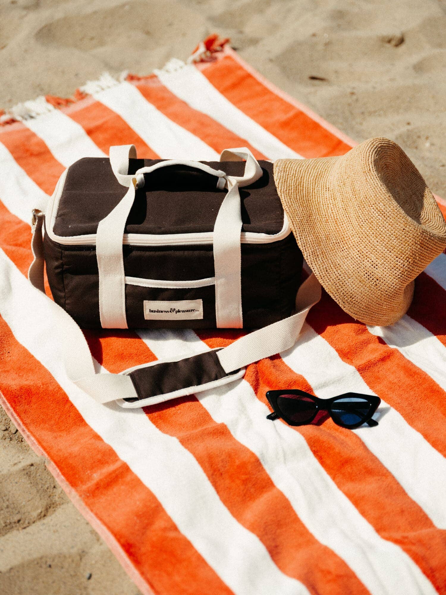 Black cooler on a sirenuse striped towel on the beach