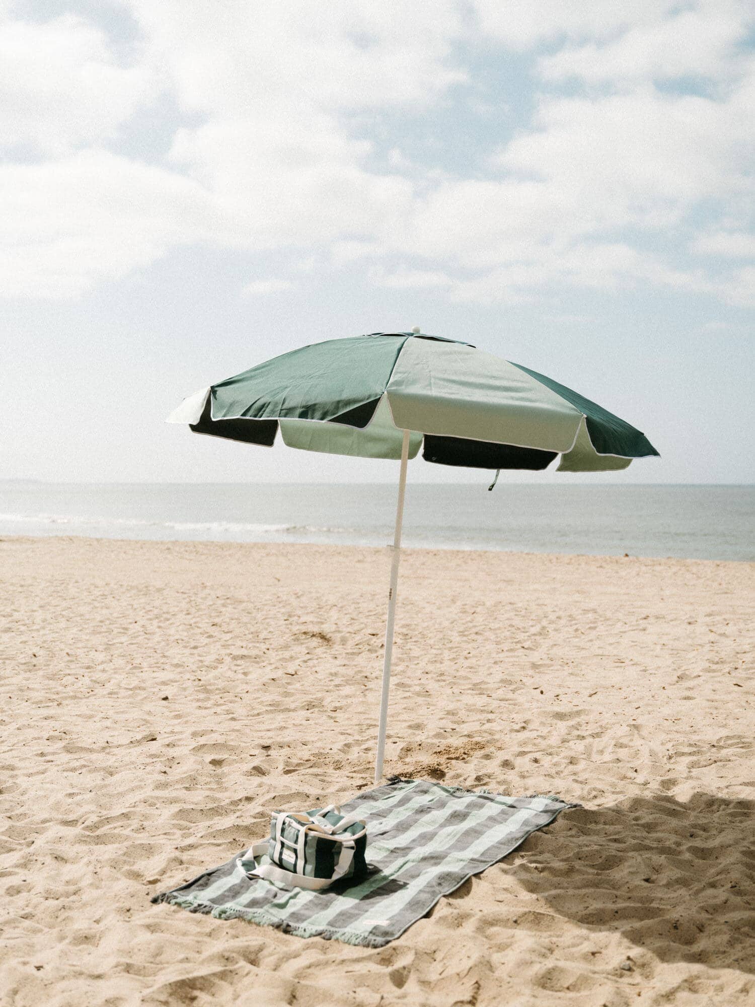 70s panel green towel, umbrella and cooler on the sand