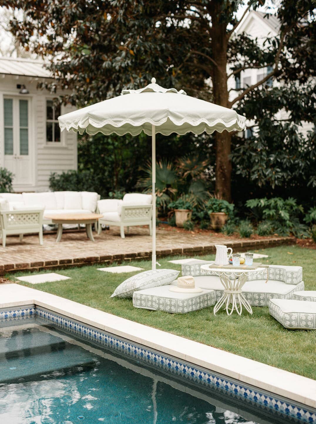 Outdoor pool area with umbrellas, chairs and outdoor cushions.
