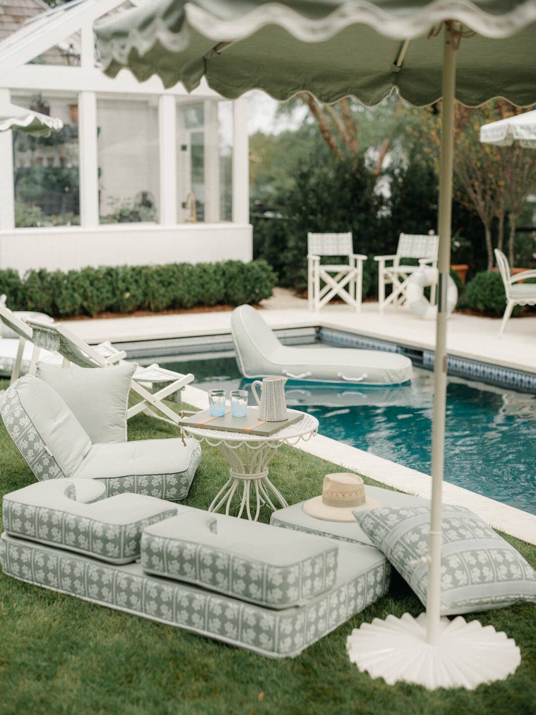 Outdoor pool area with umbrellas, chairs and outdoor cushions.