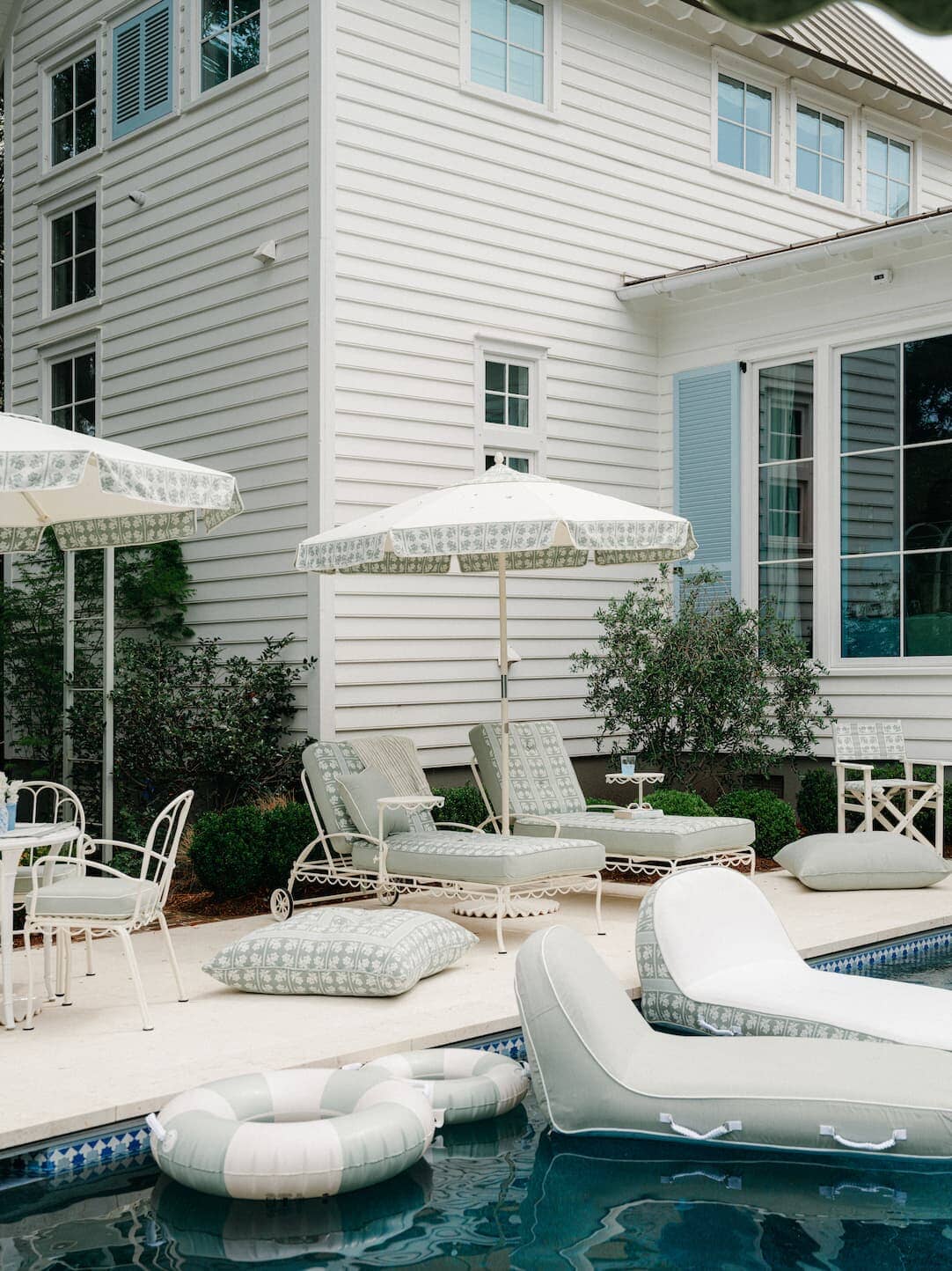 Backyard pool with umbrellas, loungers, cushions and pool loungers