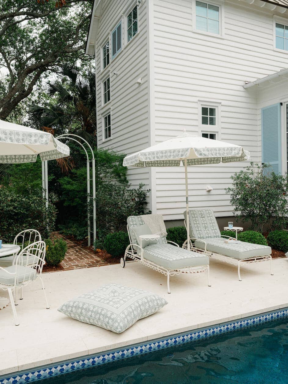Sun lounger, umbrella and floor pillow next to a pool
