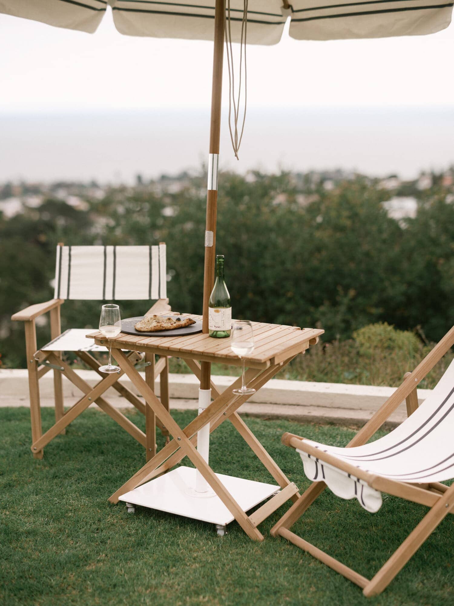 Malibu black stripe sling chair, directors chair, umbrella and tall folding table in a garden setting