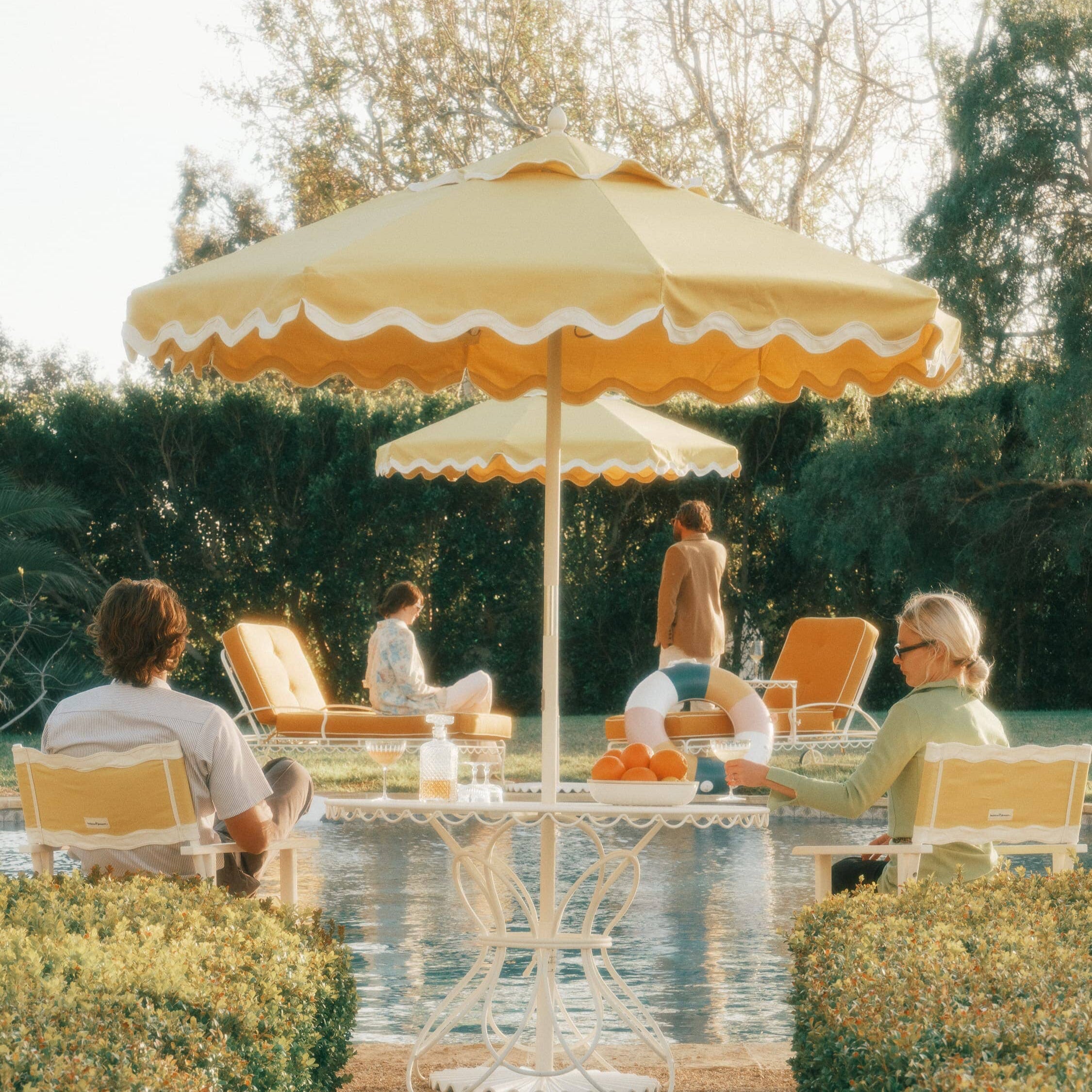 Riviera mimosa market umbrella with matching chairs next to a pool