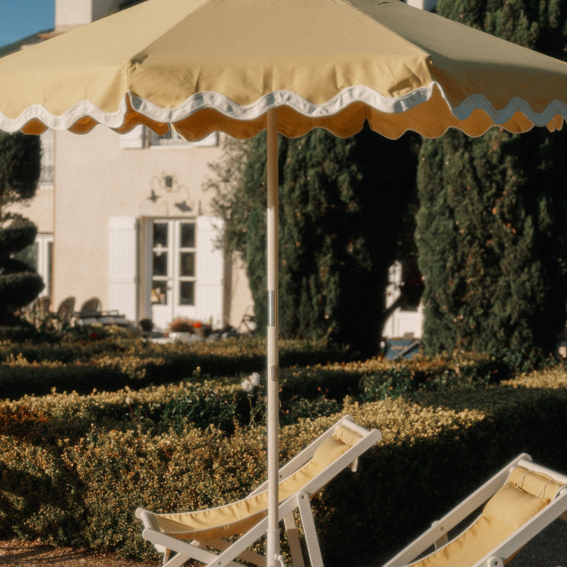 Riviera mimosa market umbrella with matching chairs next to a pool