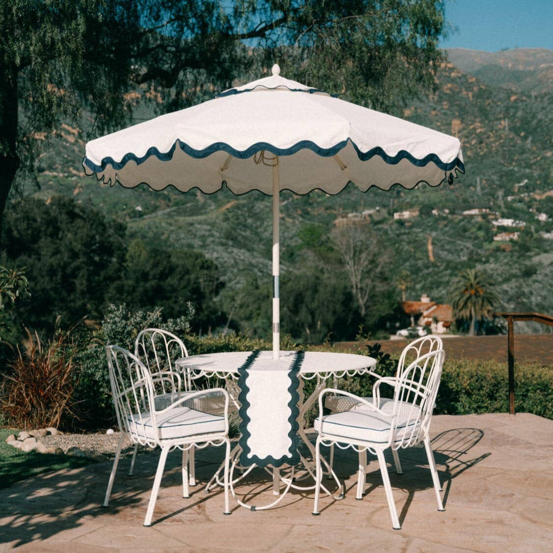 White riviera market umbrella with an alfresco dining table and chairs on a garden patio
