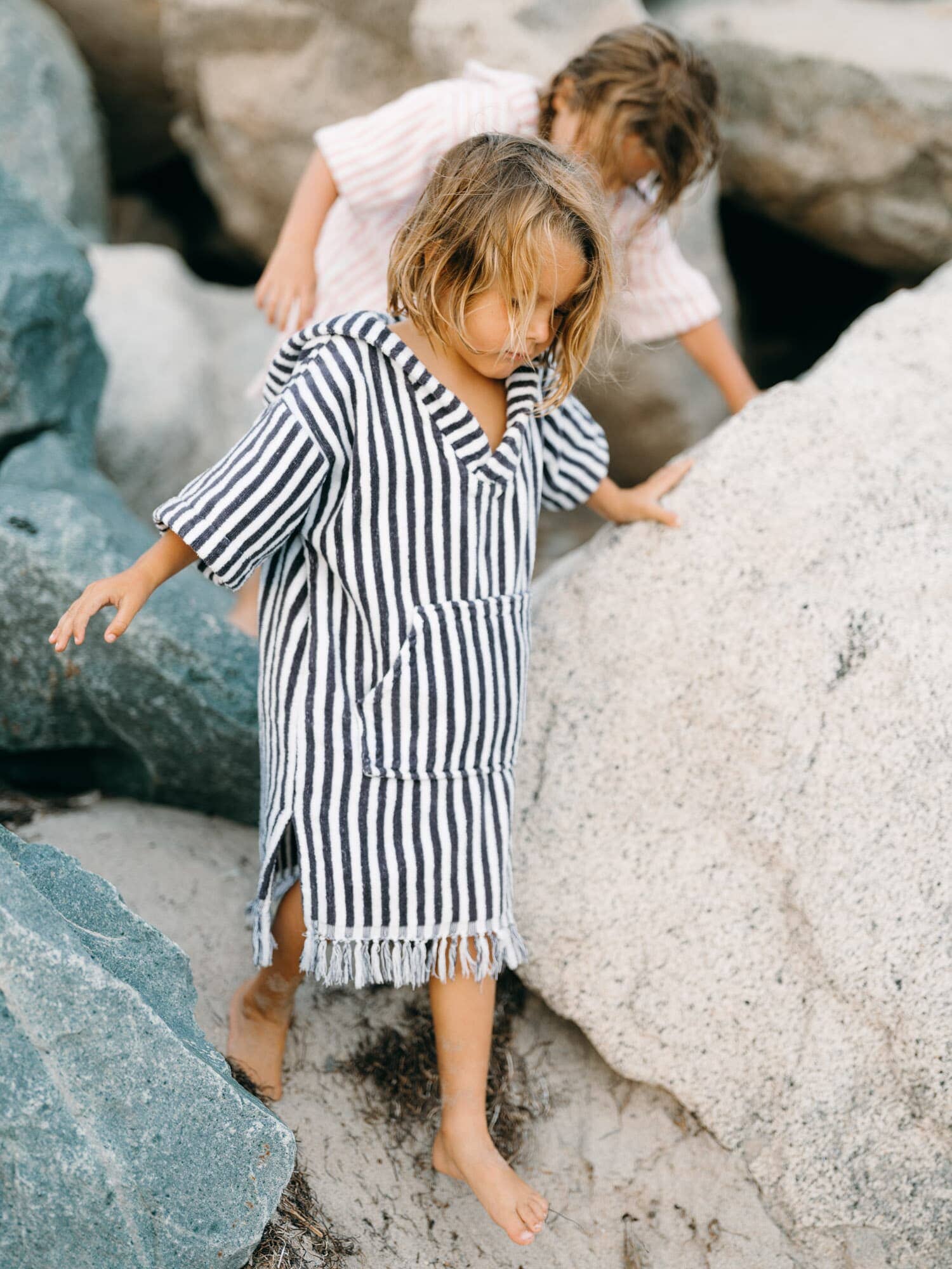 Child in navy poncho climbing on rocks