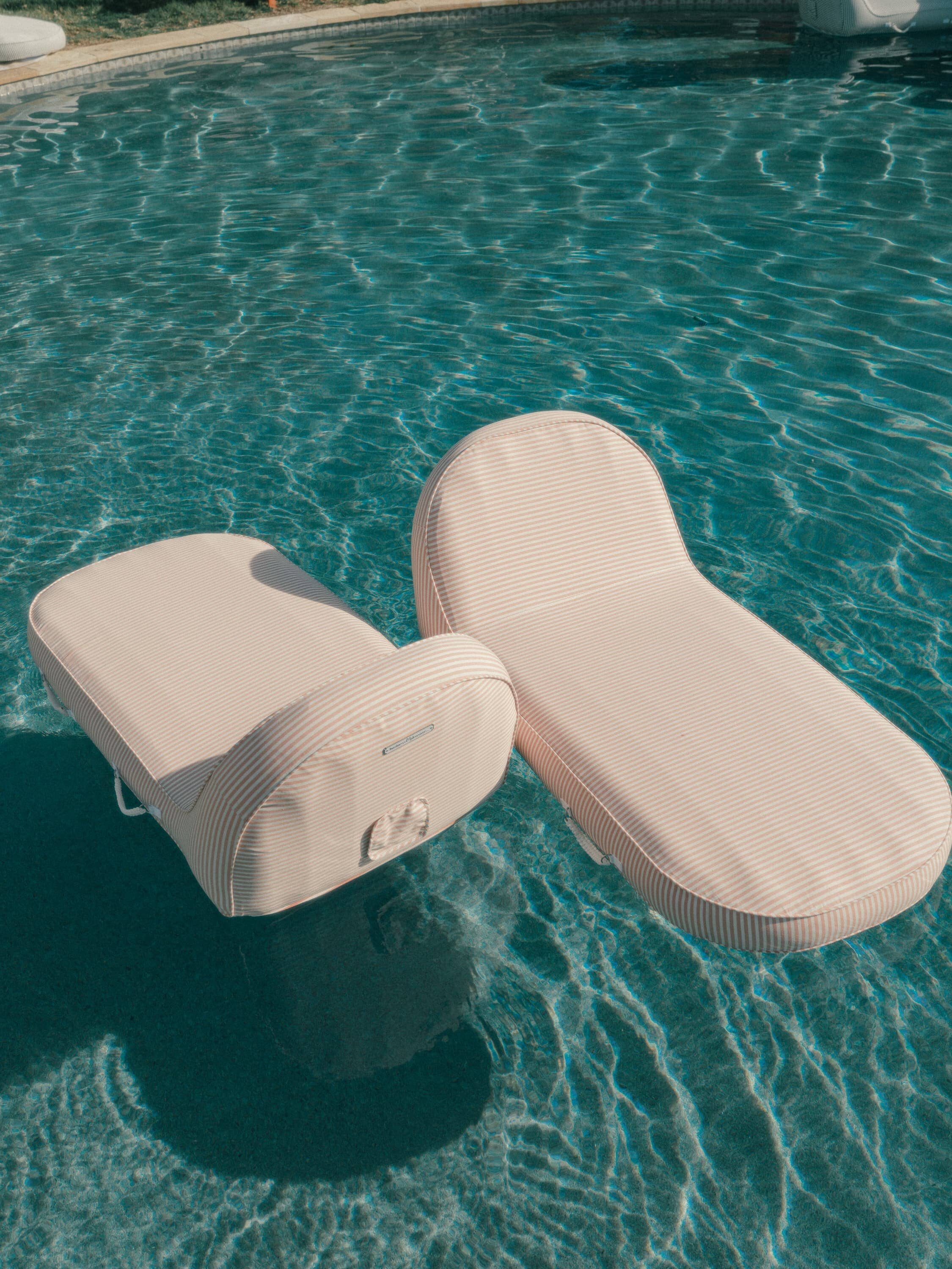 pink pool loungers floating in a pool