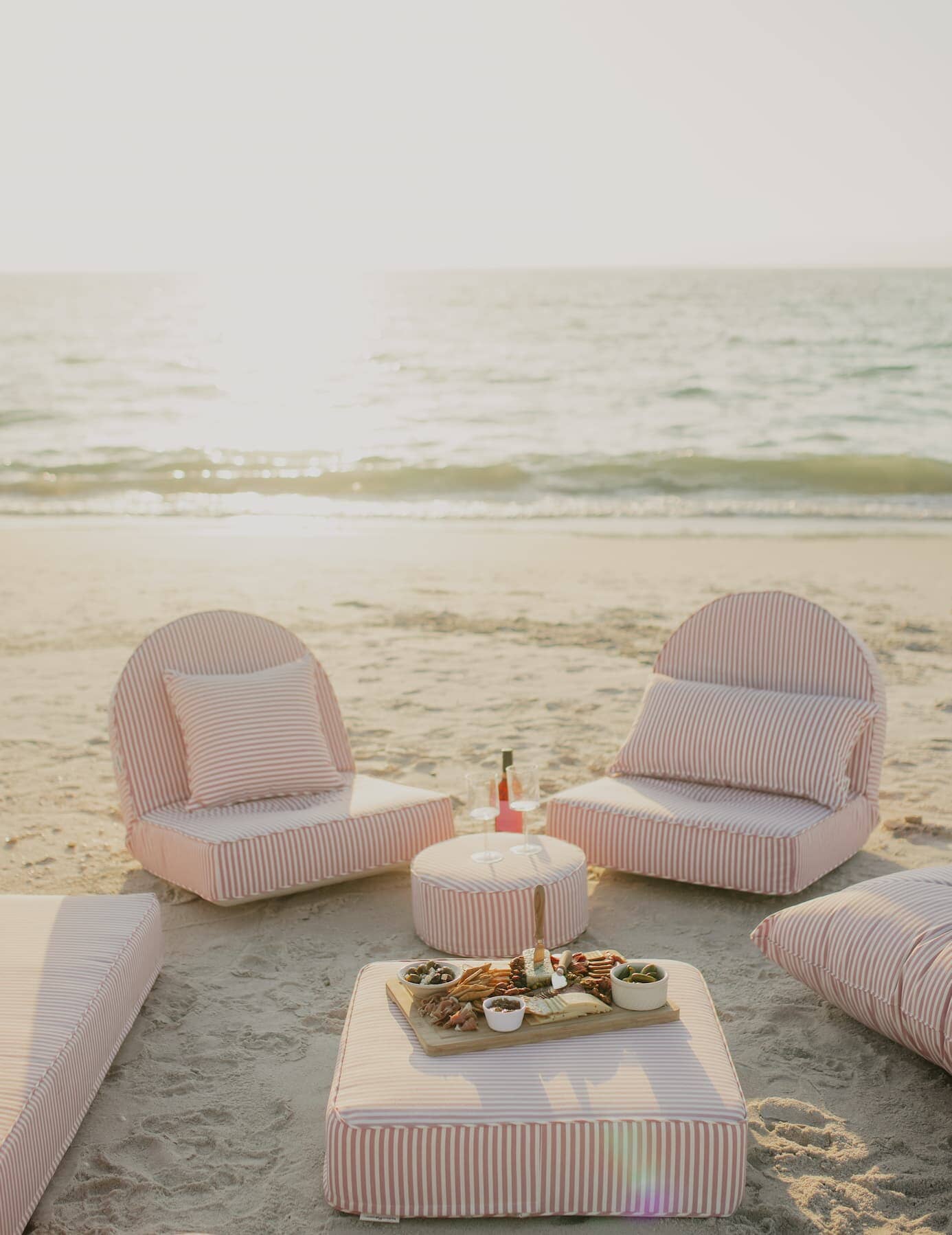 pink reclining loungers on the beach with a picnic