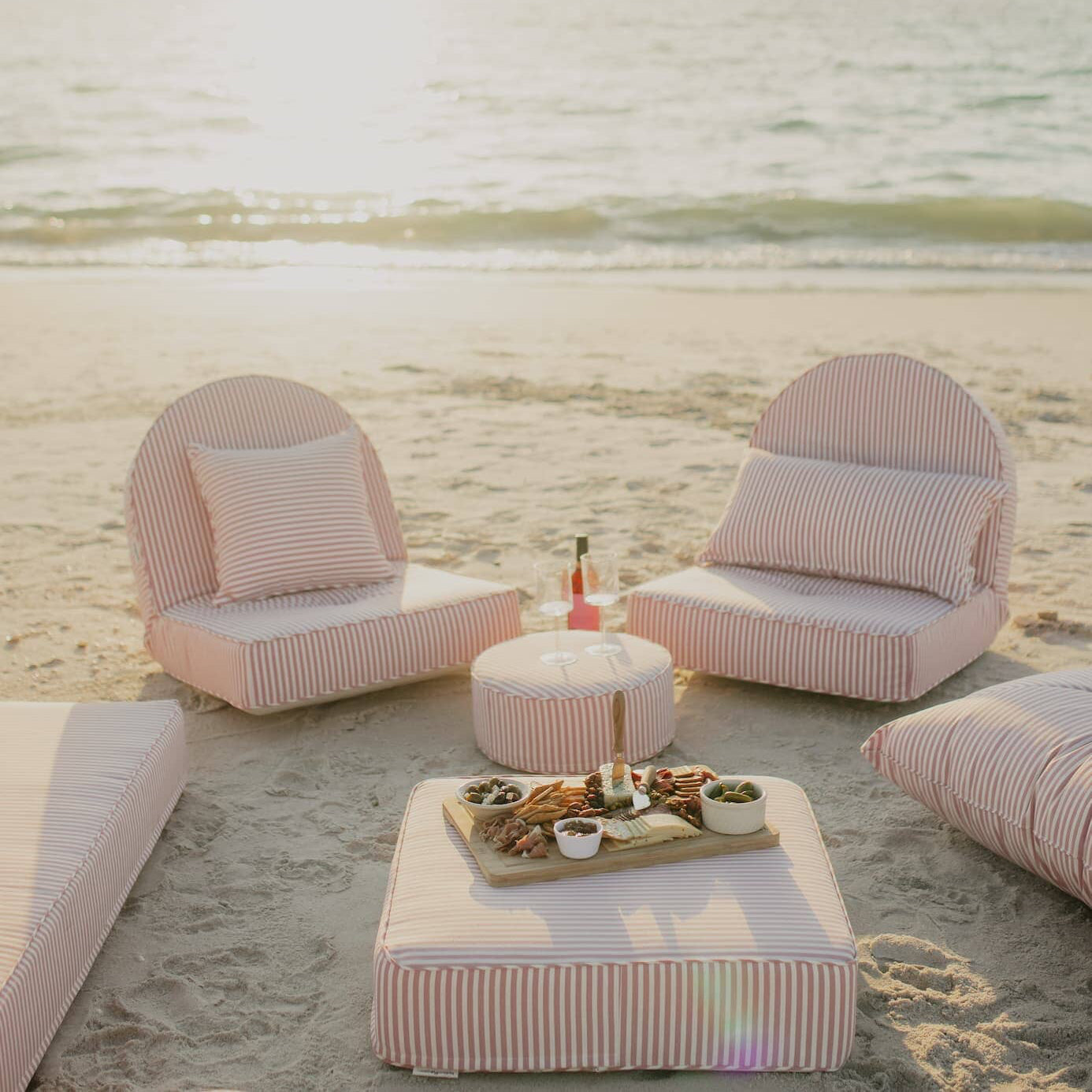 pink reclining loungers on the beach with a picnic