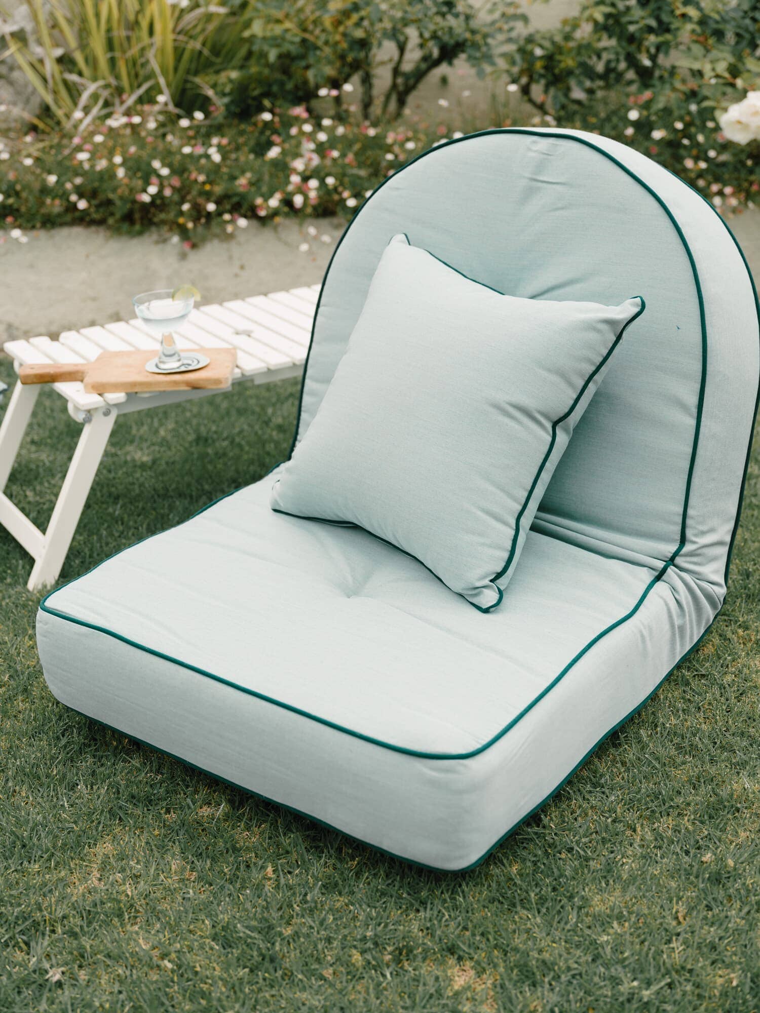 Small throw pillow on reclining lounger in garden setting