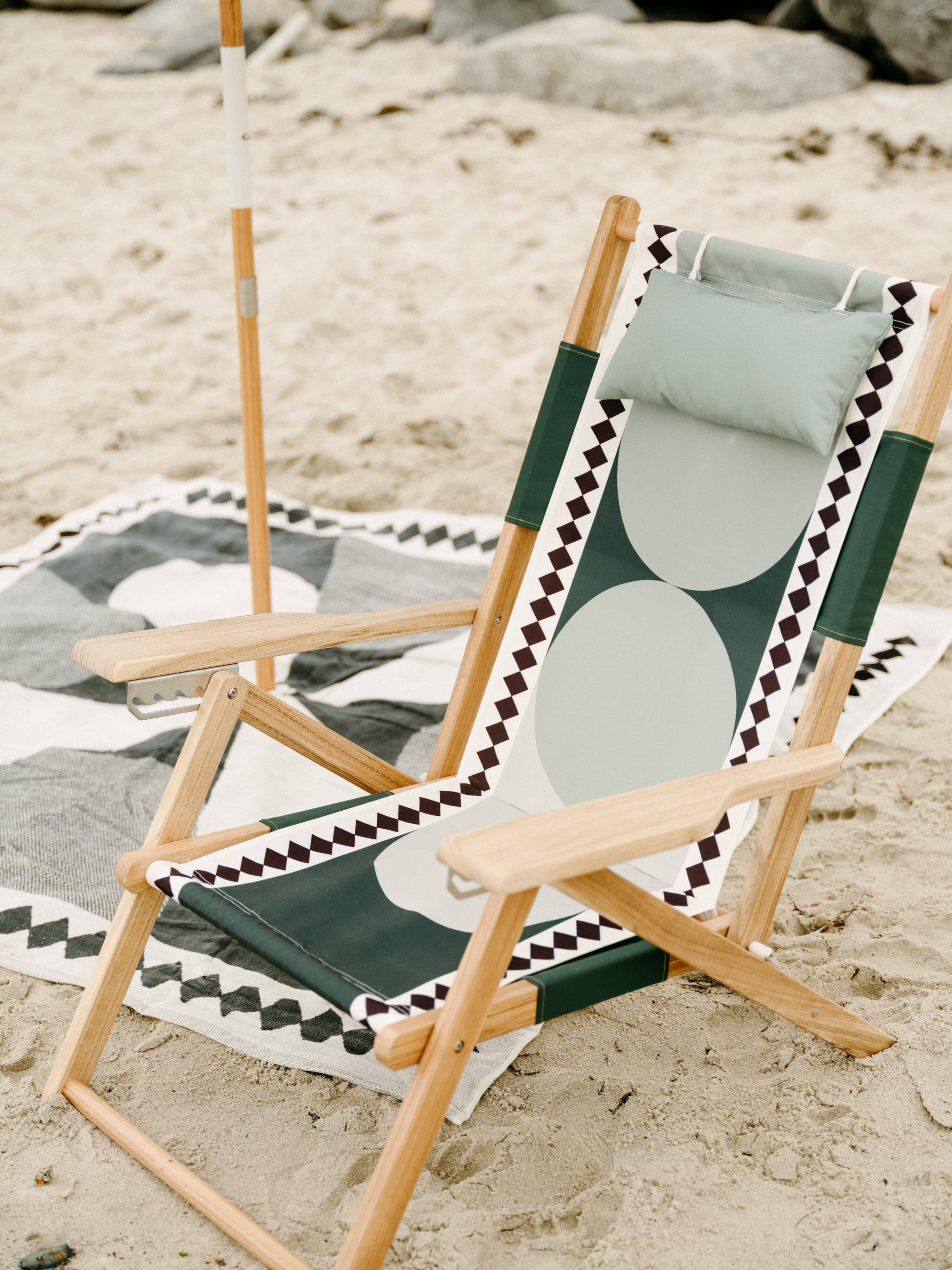 Beach set up with diamond green umbrella, chair and blanket.