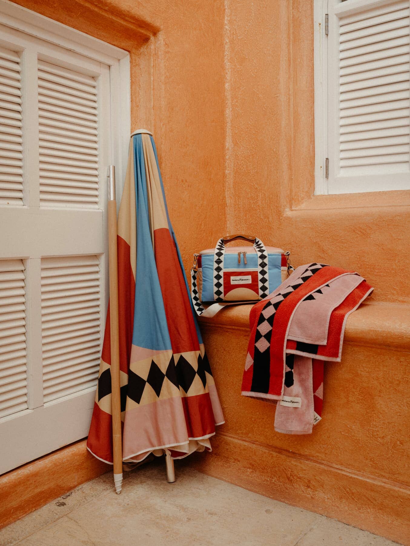 pink diamond cooler, umbrella and towel on stone step