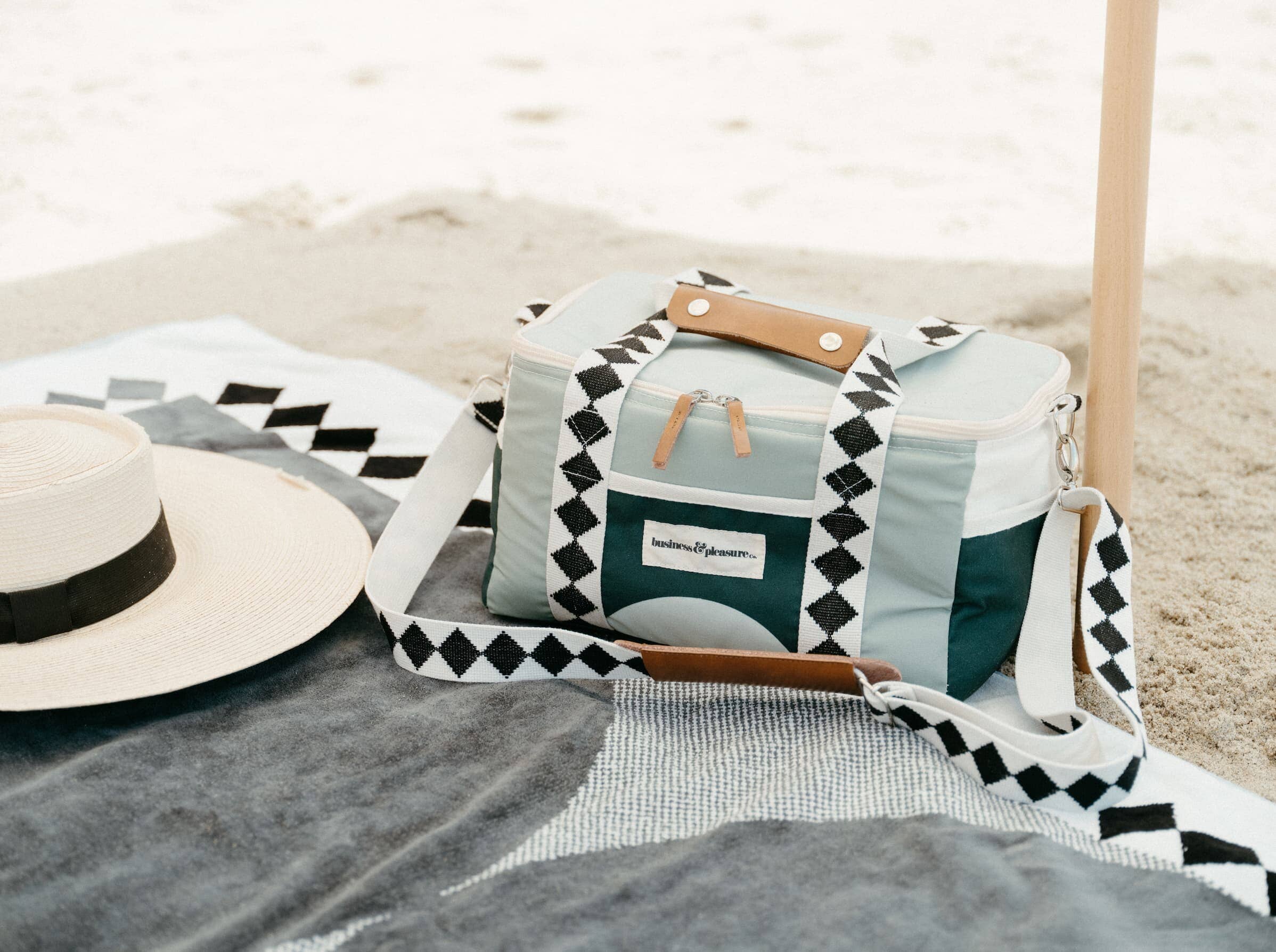 green diamond cooler on beach with towel and umbrella