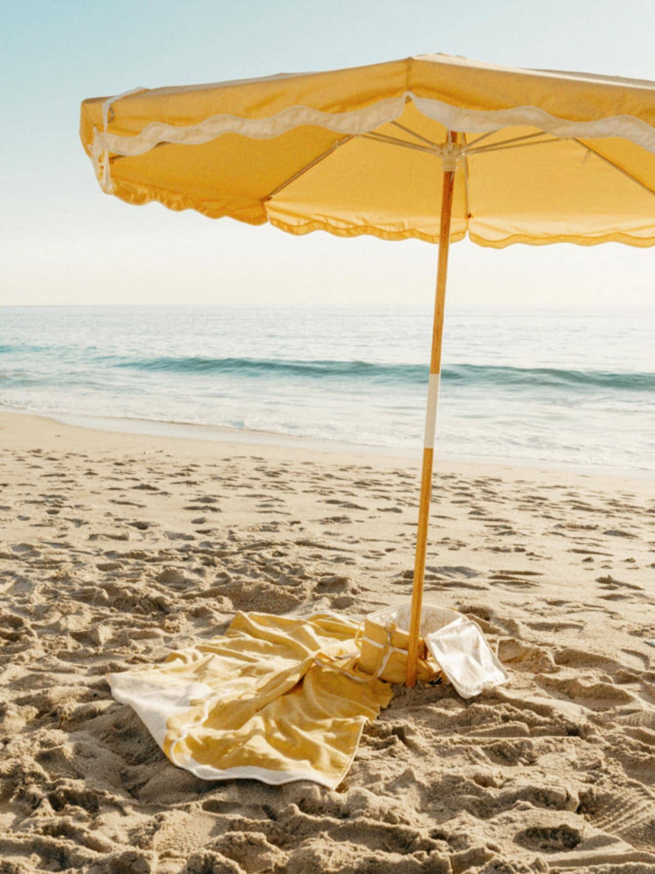 Beach setting with riviera mimosa umbrella, towel & cooler