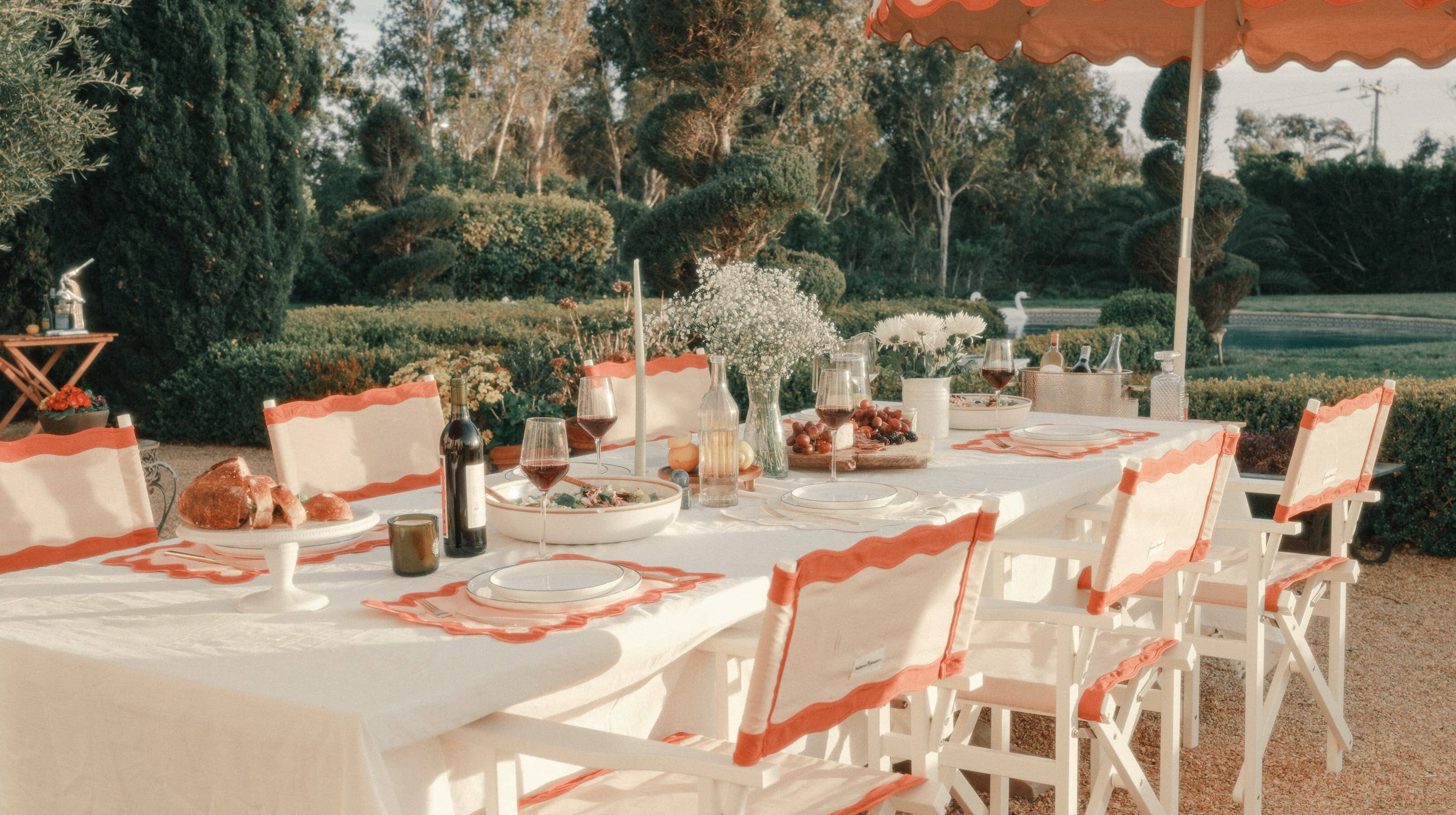 al fresco dining table with riviera pink directors chairs and market umbrellas