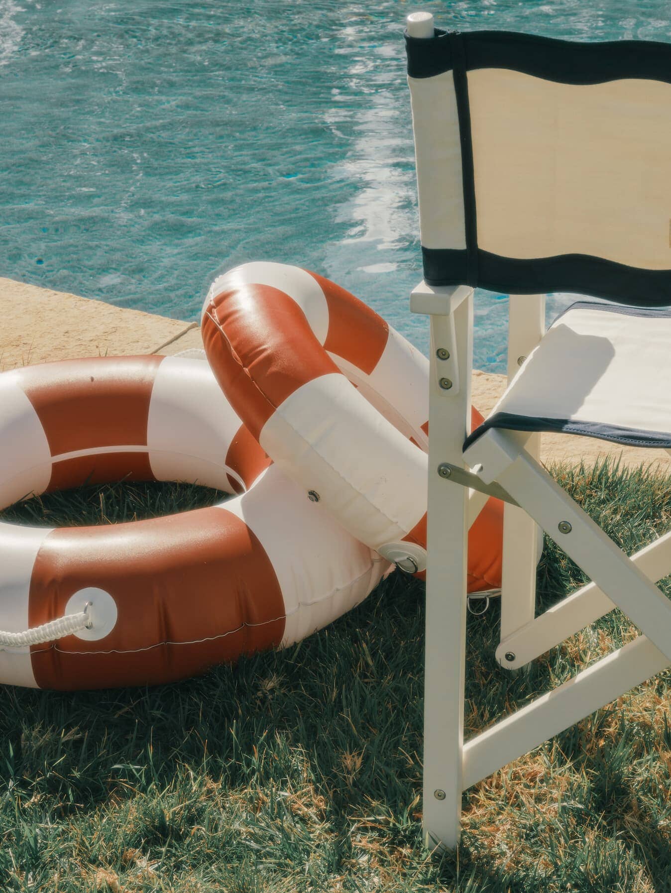 white riviera directors chair next to a pool with red pool floats