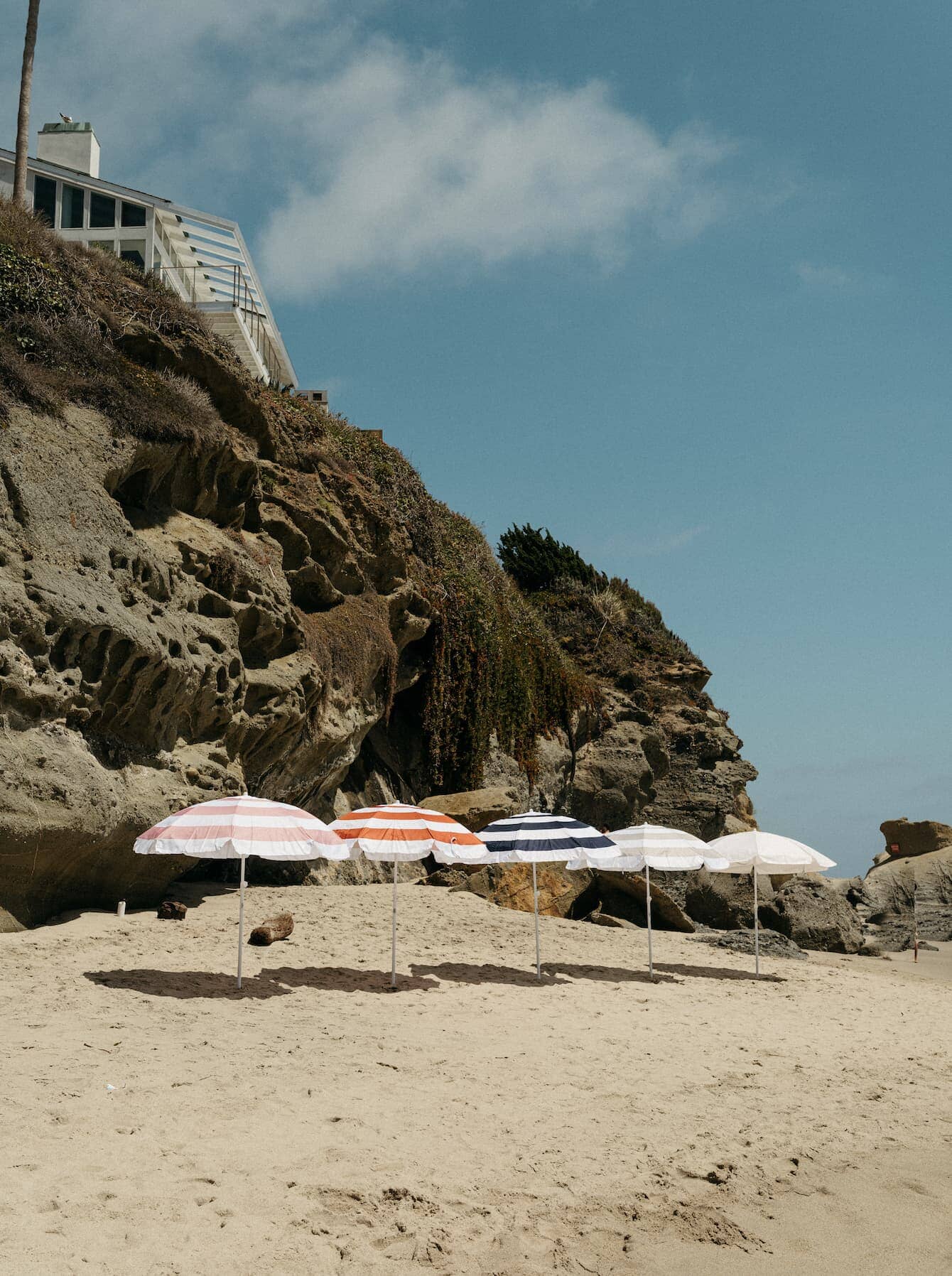 5 family umbrellas lined up on the beach