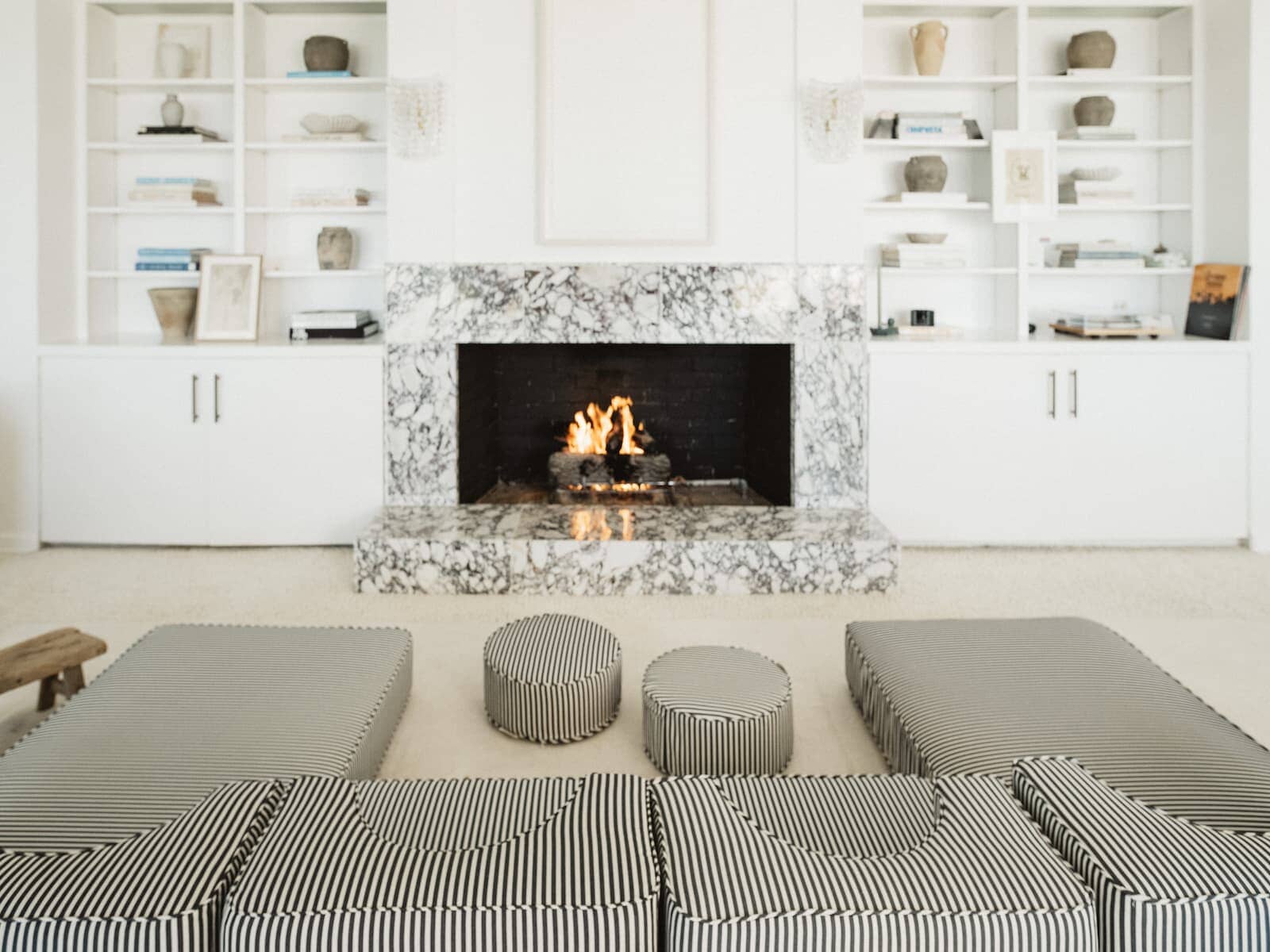The navy stripe modular pillow stack arranged in front of a living room fire place