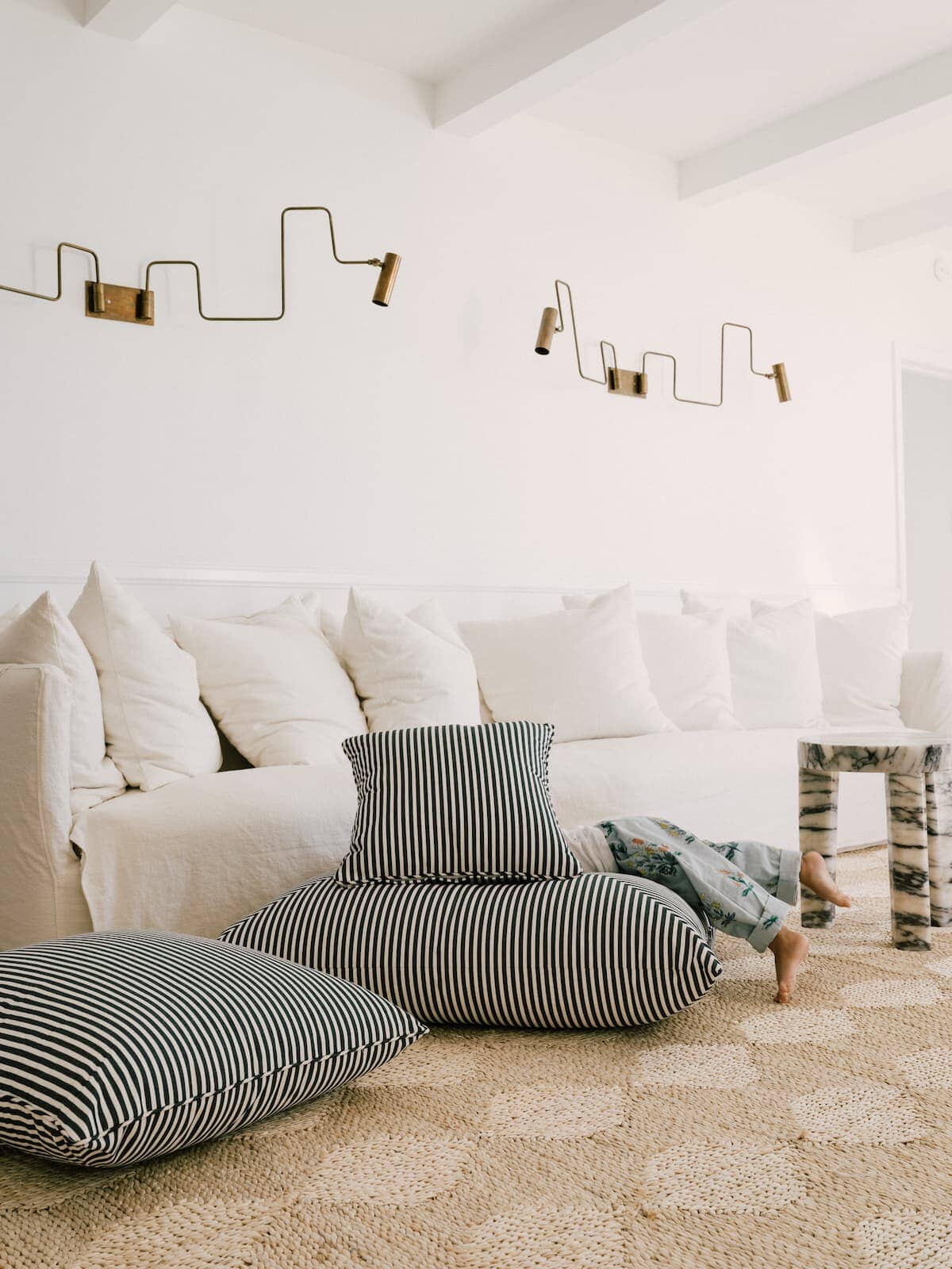 3 outdoor cushions stacking in a living room with a child playing