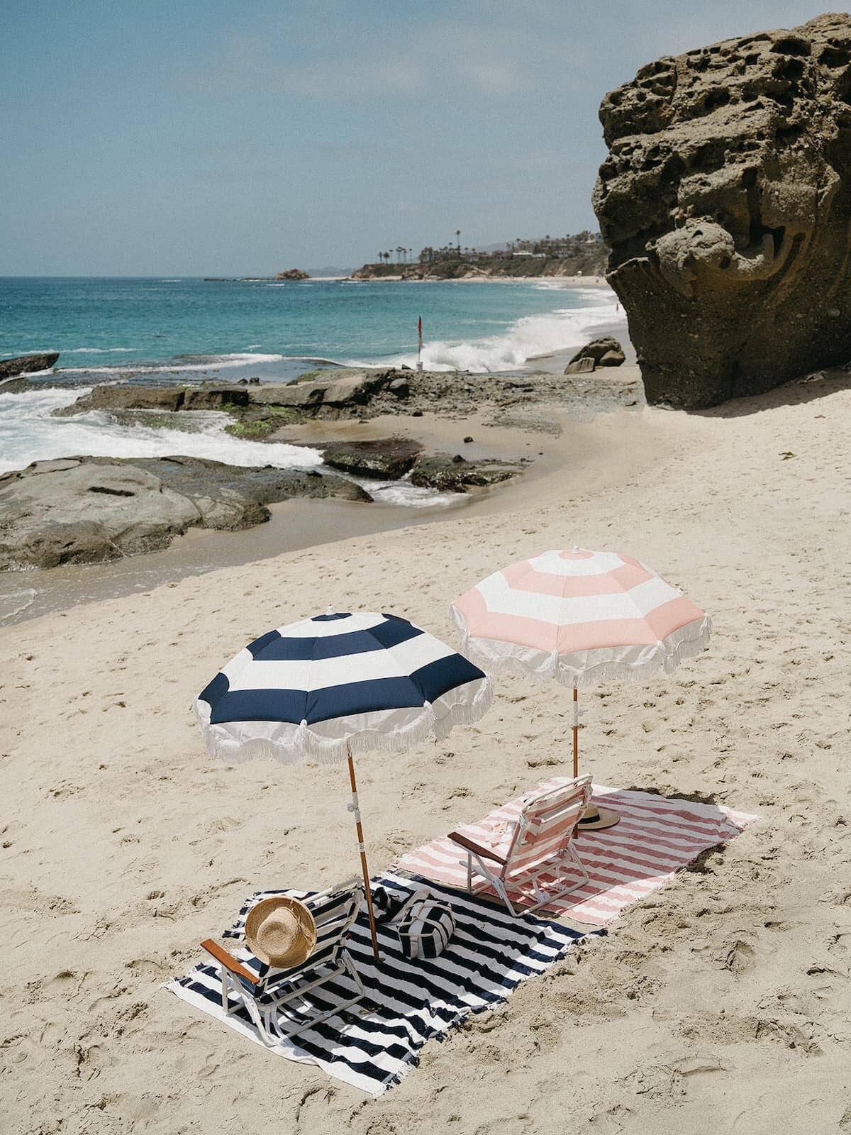 beach setting with navy and pink umbrellas, blankets and chairs
