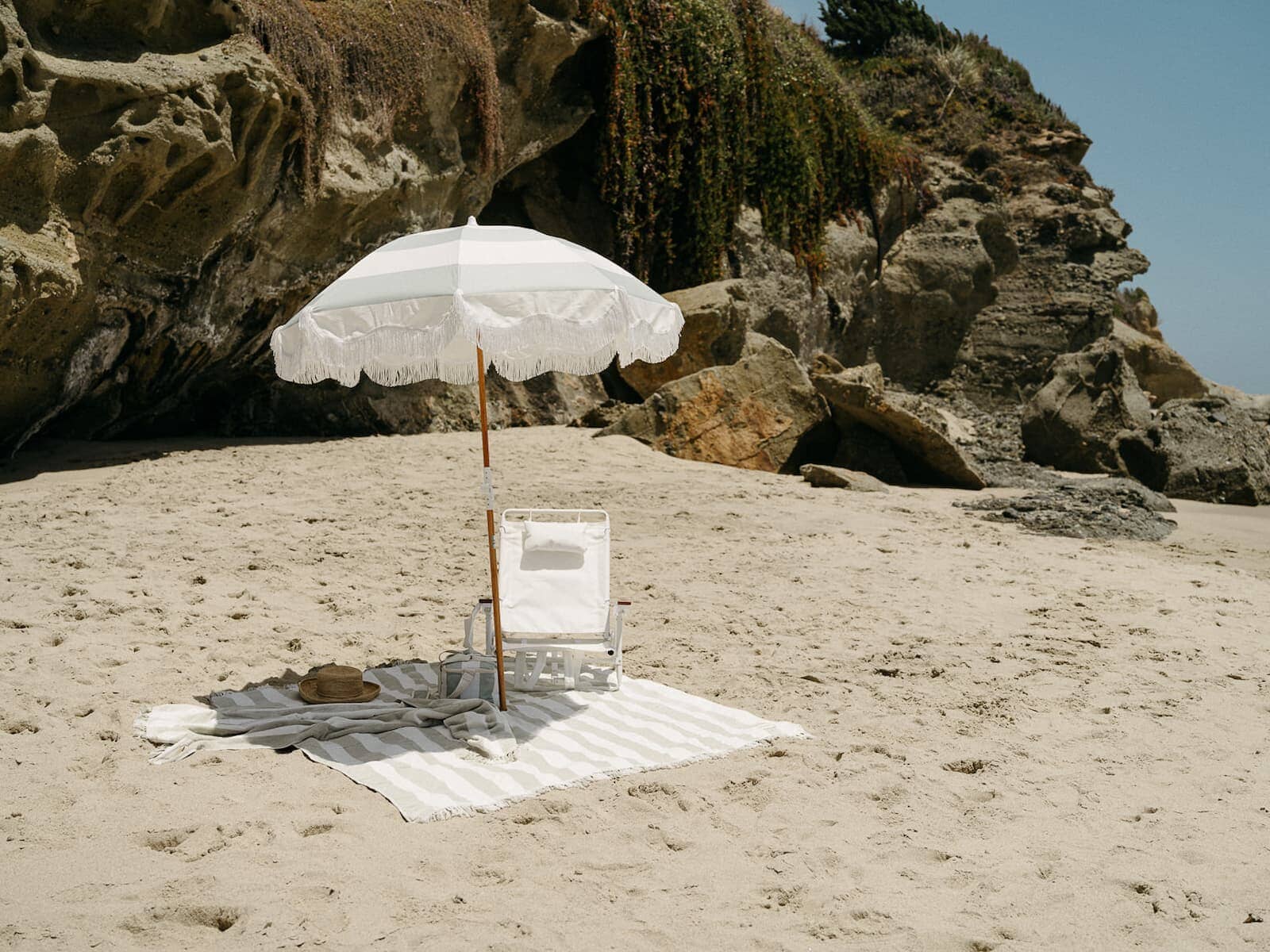 beach setting with sage stripe umbrella and blanket