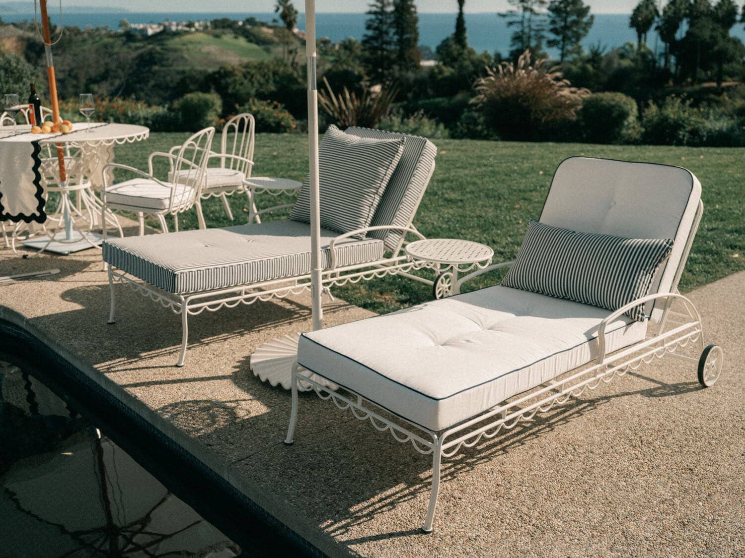 white sun loungers next to a pool with white and navy stripe cushions