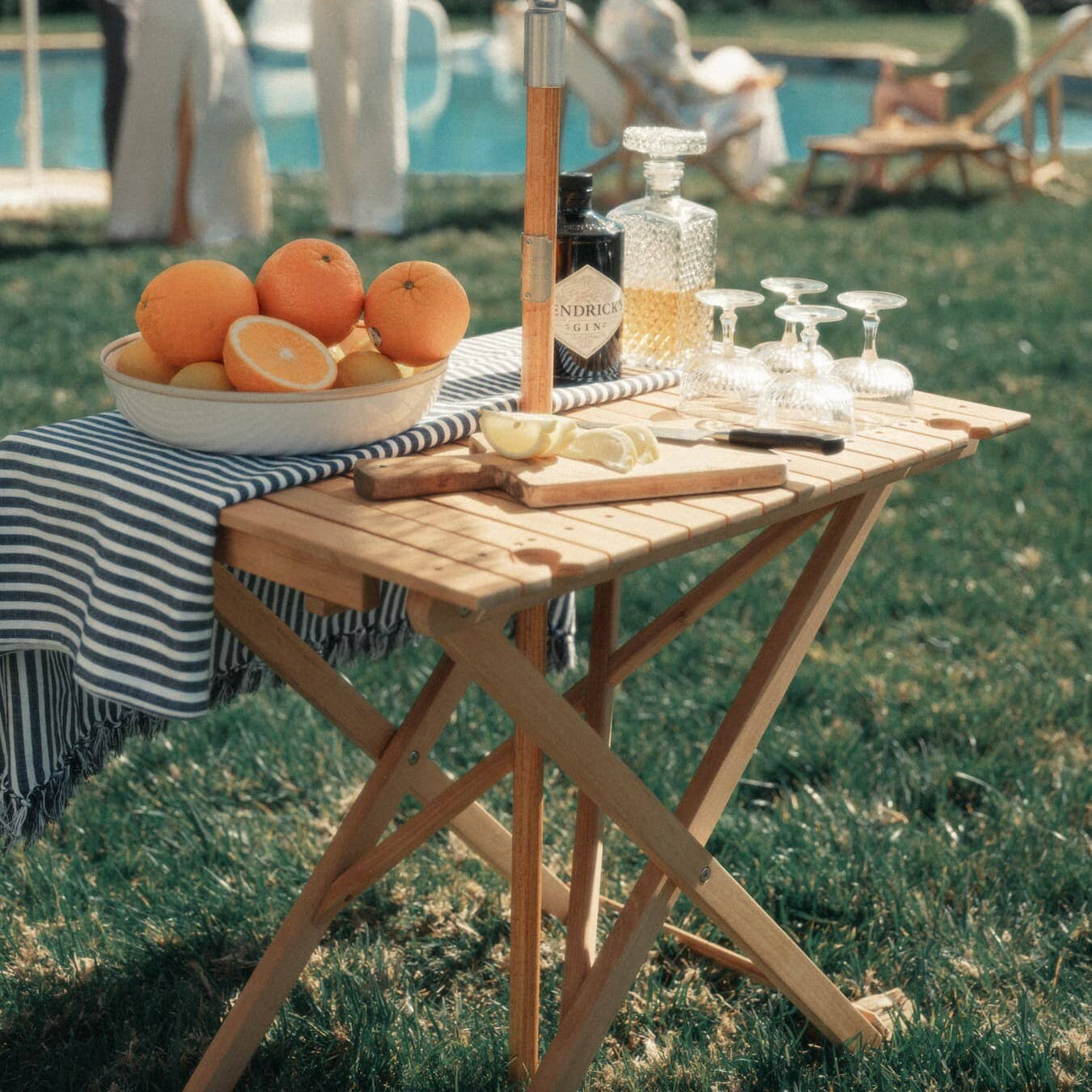 Outdoor picnic setting with tall folding table with drinks and fruit