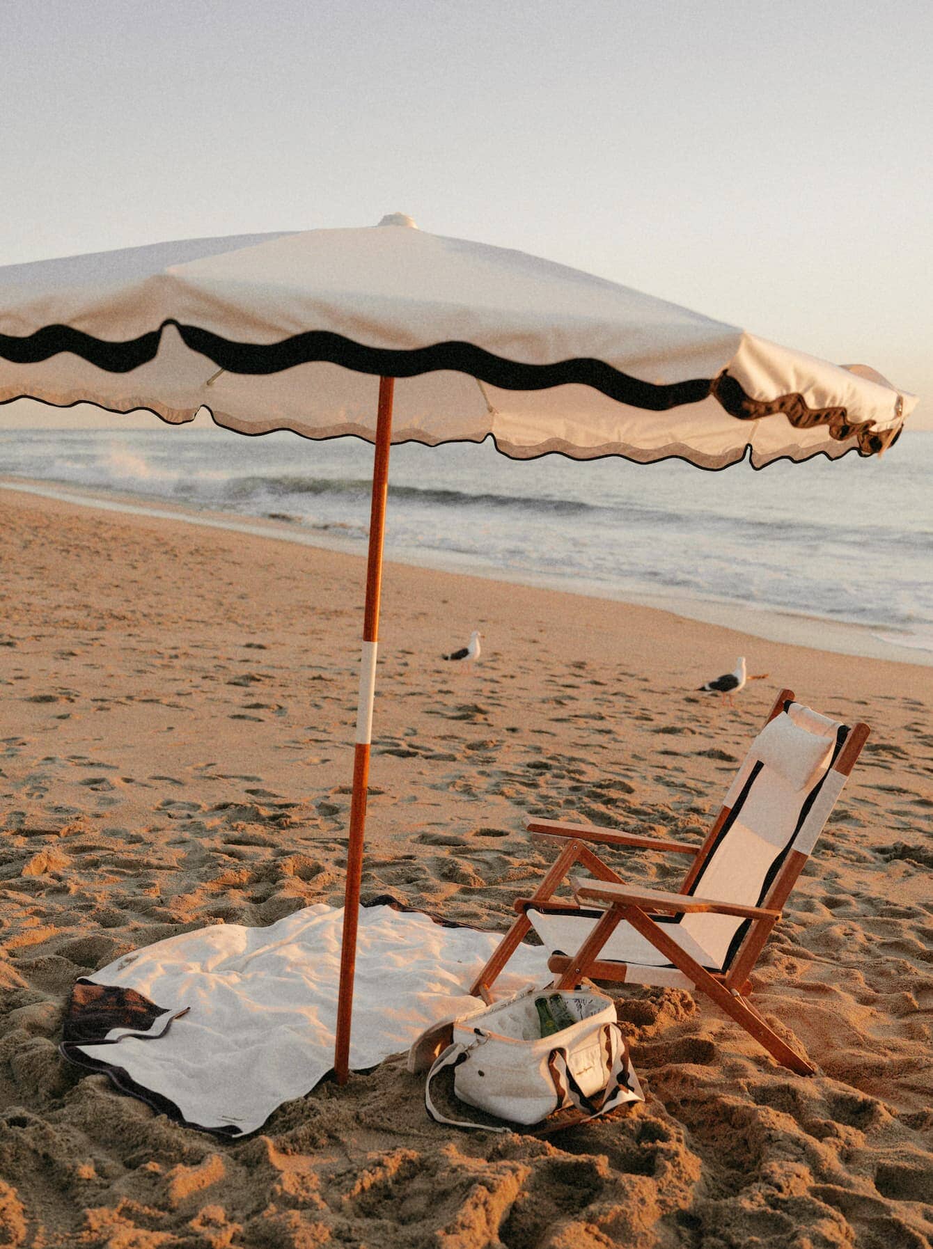 Beach setting with Riviera White umbrella, chair, towel & cooler