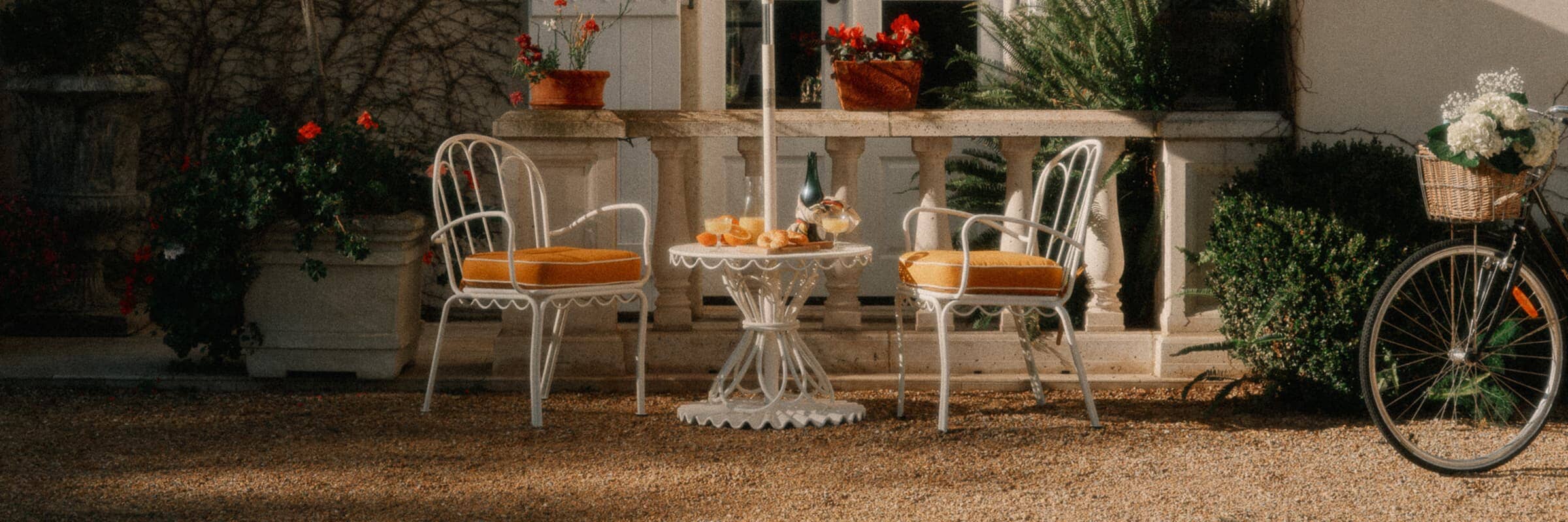 small metal table with two chairs and an umbrella in a courtyard