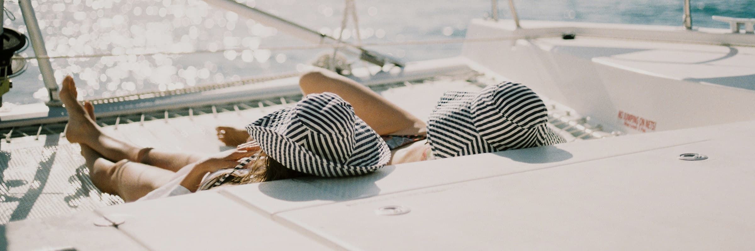 two people laying on a boat deck with blue striped hats
