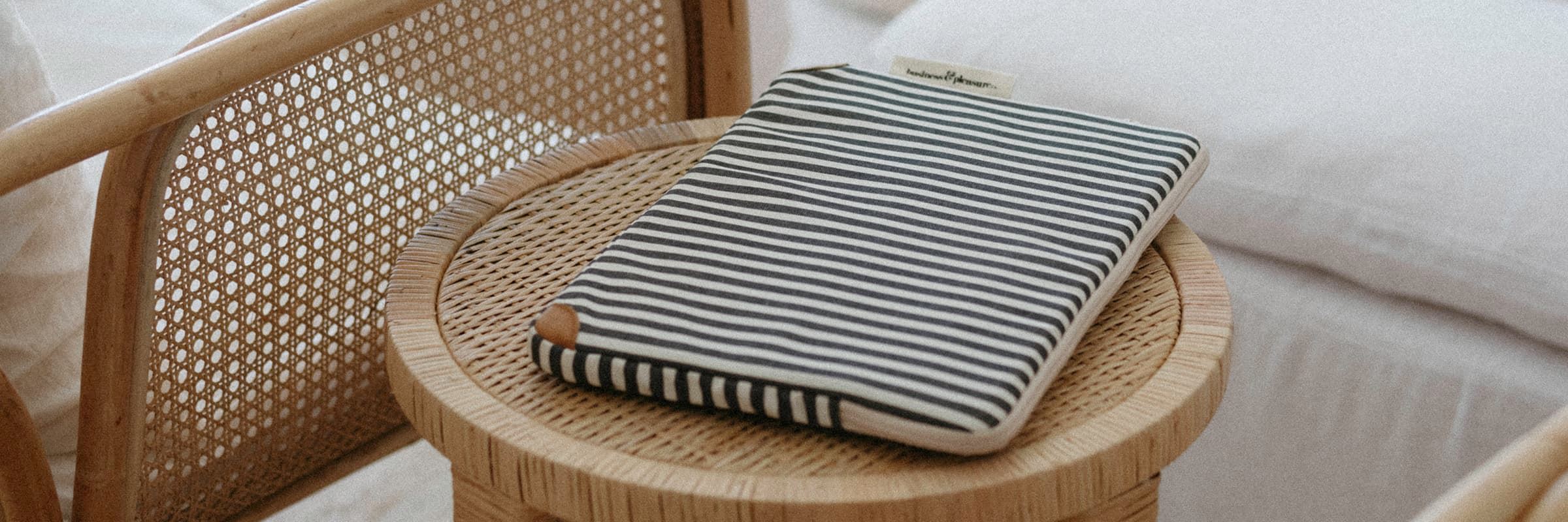 navy striped laptop case on a rattan side table in a living room