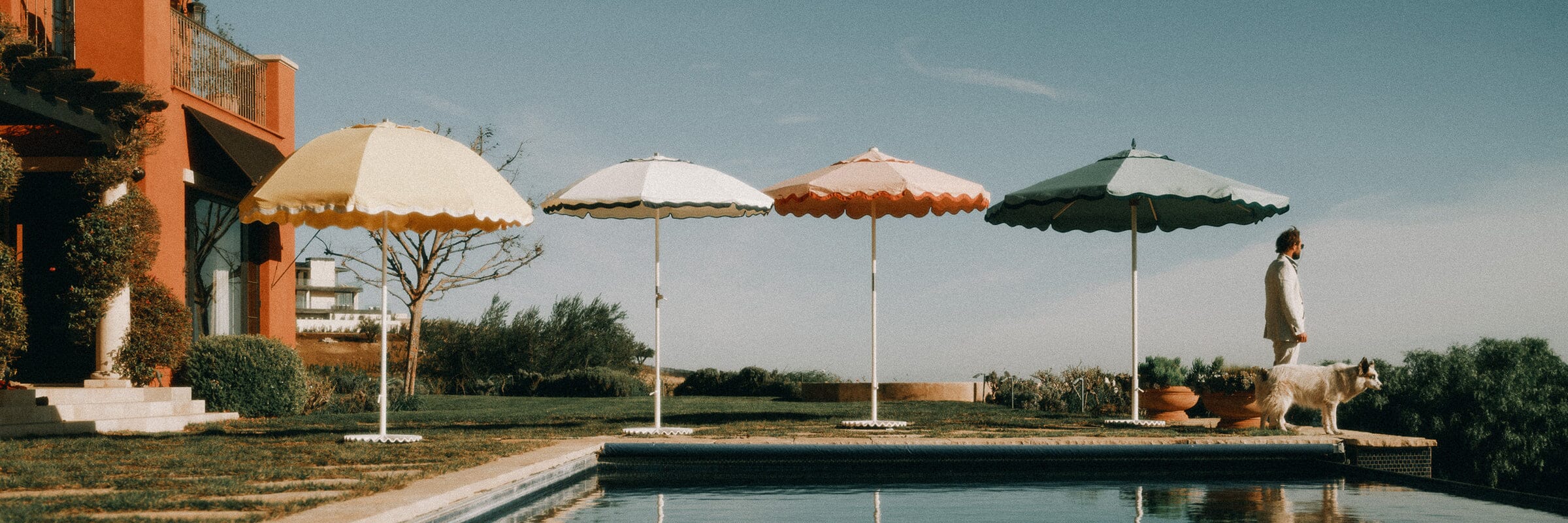 four colorful beach umbrellas on the sand with beach towels under them