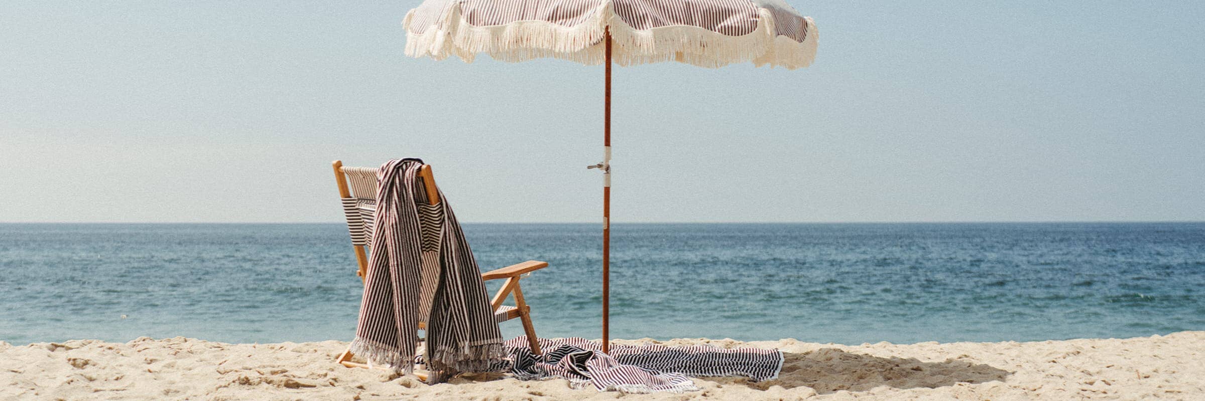 blue striped chair and umbrella with a beach towel on the sand
